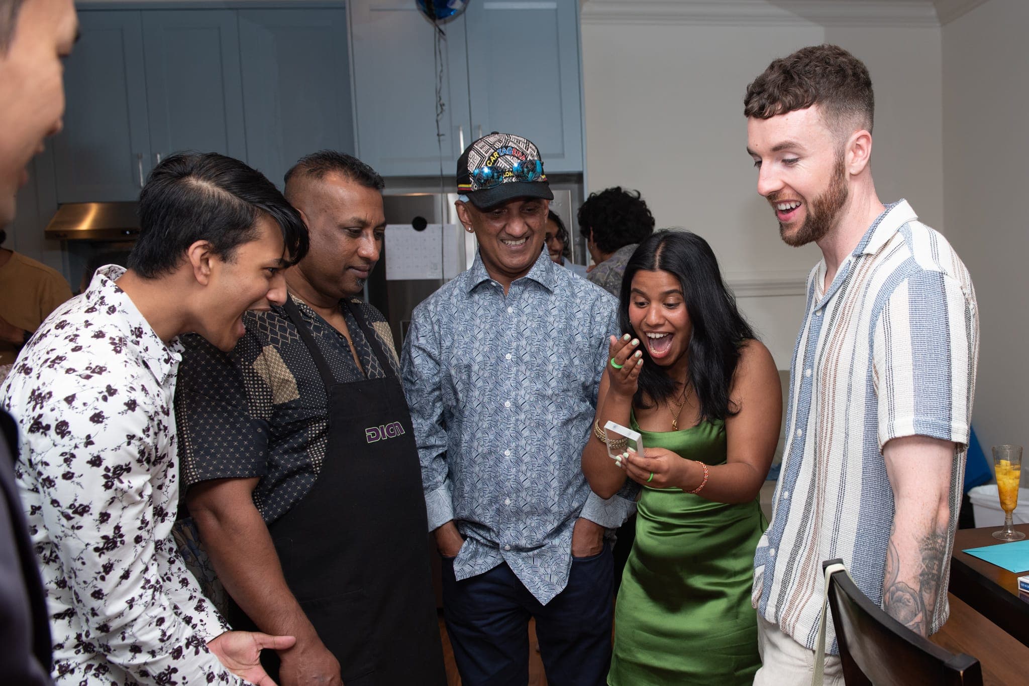 A group of guests laughing together during close-up magic at a private celebration