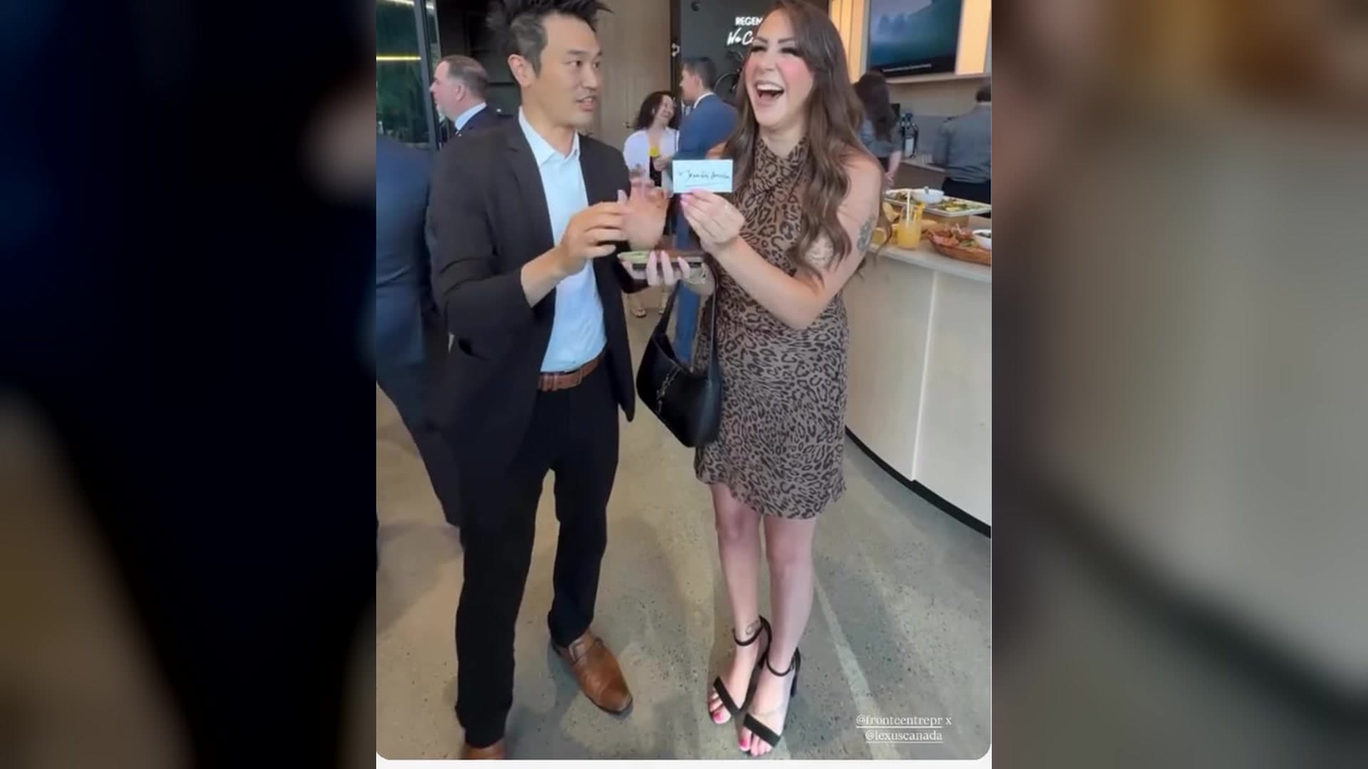 A guest laughing as she holds up the card Kel just revealed at the Studio by Regency Lexus grand opening in Burnaby