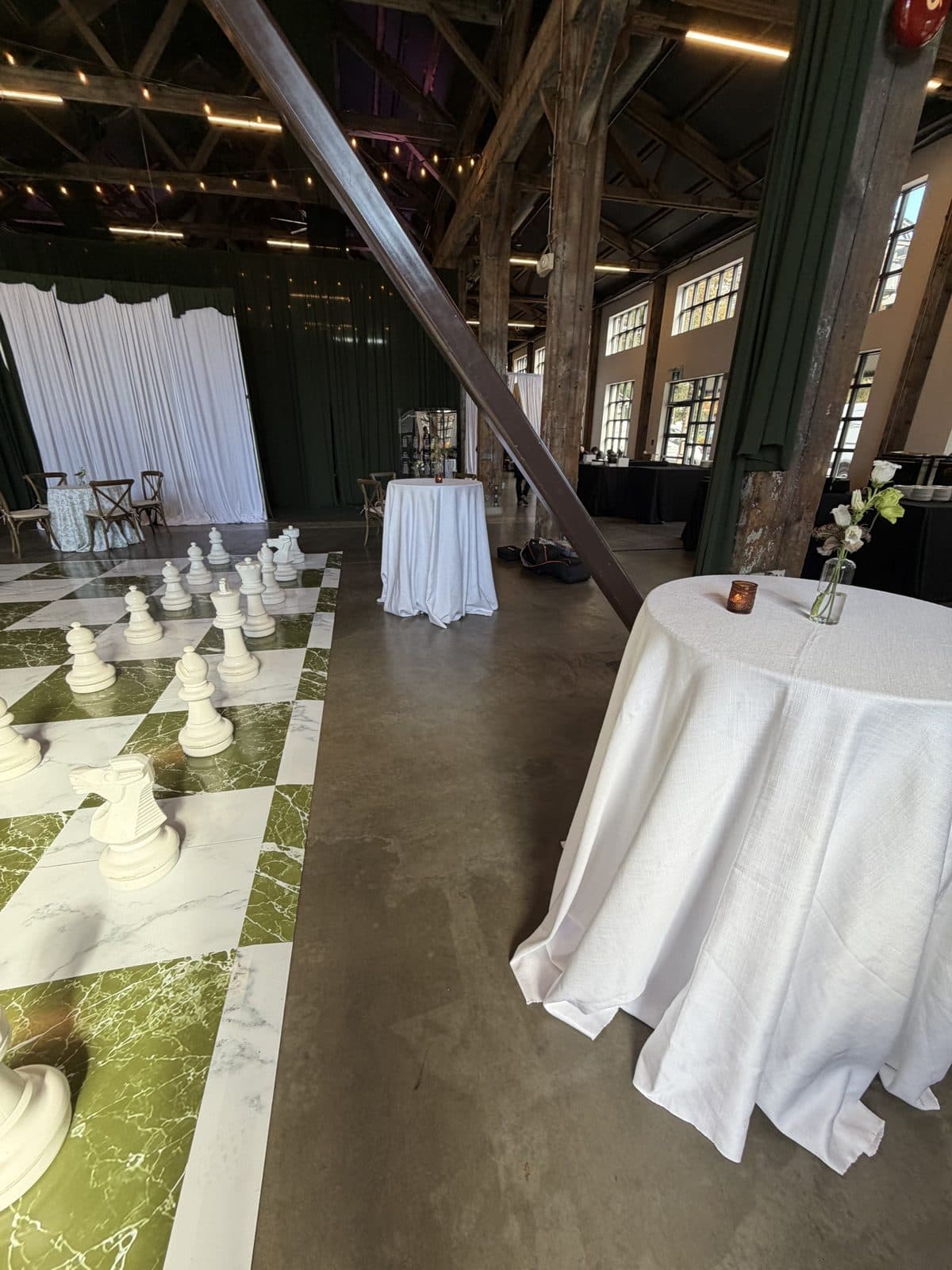 A giant white chess set on a green marble checkerboard floor at The Pipe Shop, North Vancouver, set for Shiva and Conner's wedding