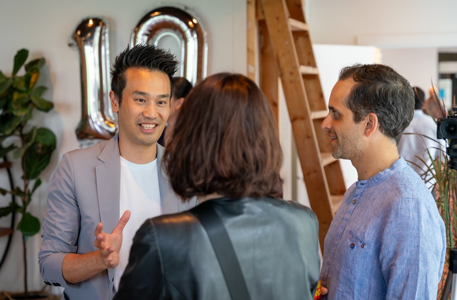 Kel performing close-up magic for guests under a silver 10 balloon at Vireo Video's 10 year anniversary party in Vancouver