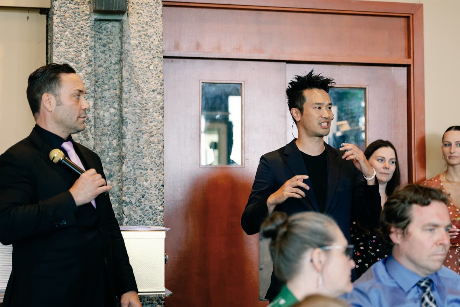 Vancouver MC Mike Oulton with Kel in front of seated guests at a reception