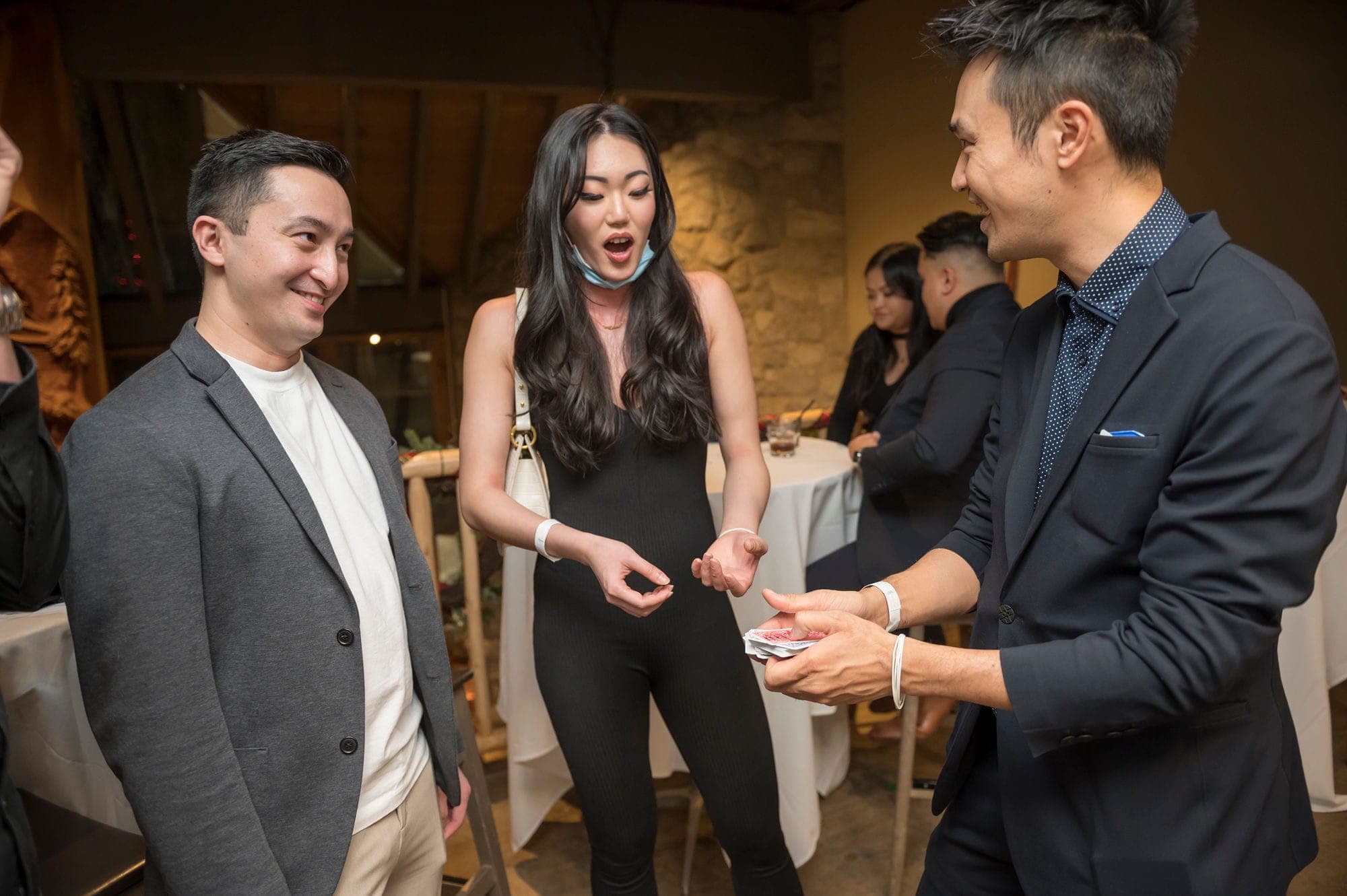 A guest reacting with an open-mouthed gasp to a card reveal during cocktail hour at a Vancouver event
