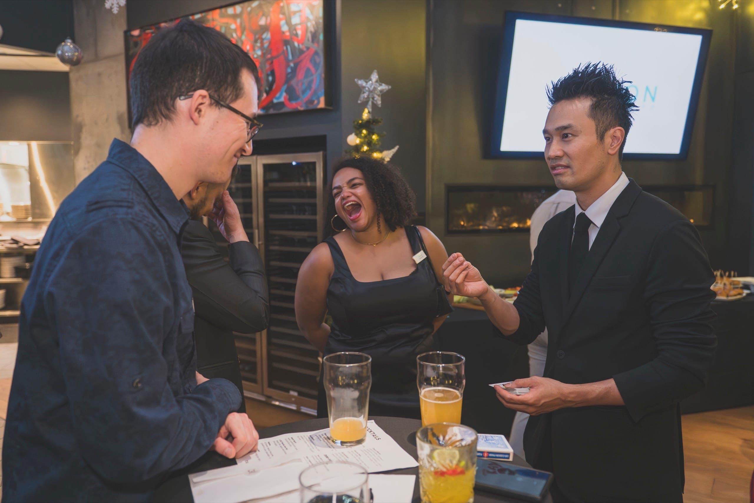 A guest laughing with delight during close-up card magic at a Vancouver cocktail reception