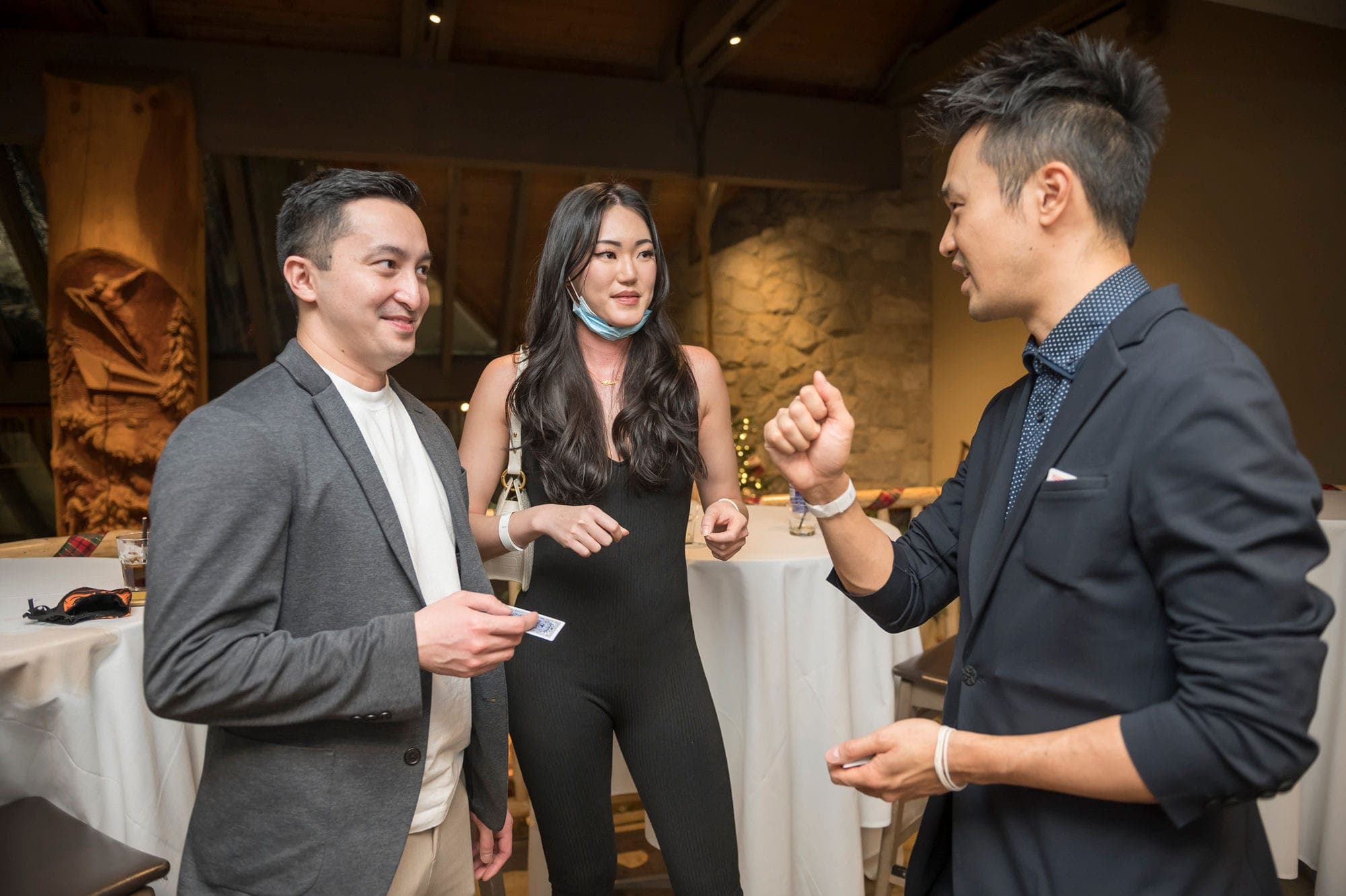 Three guests watching a card routine together at a Vancouver client appreciation evening