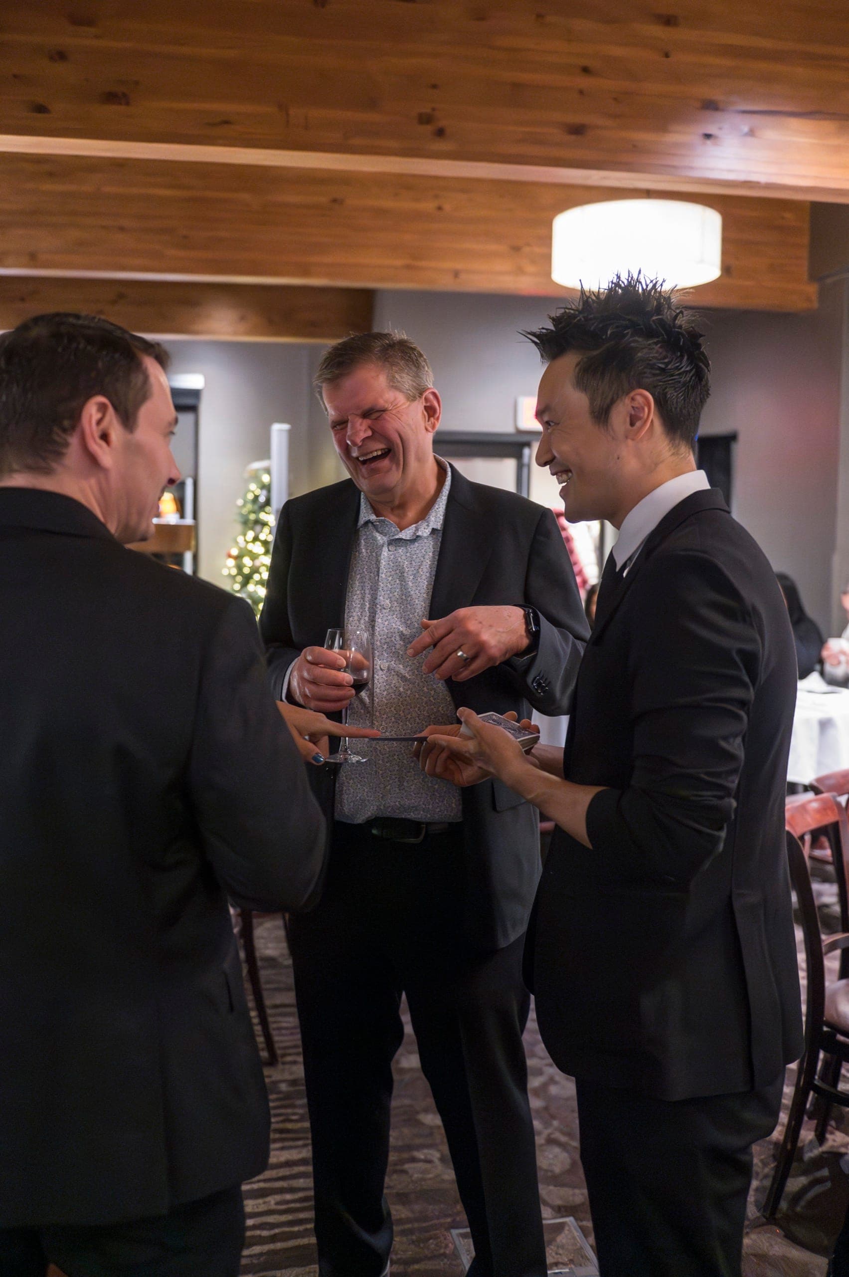 A guest doubled over laughing during close-up card magic at a Vancouver corporate holiday party