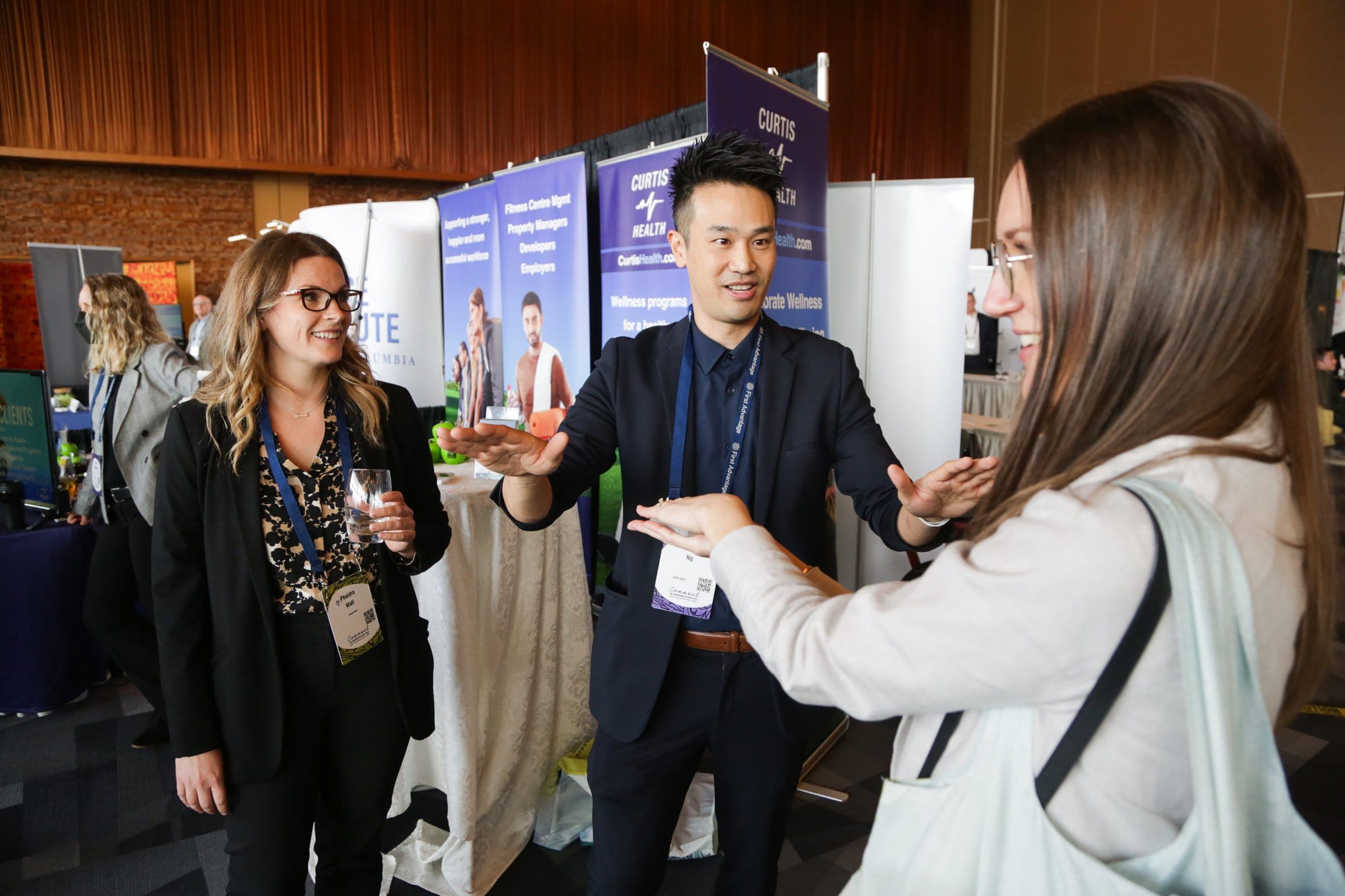 Kel performing close-up magic for attendees at a trade show booth during a Vancouver conference expo