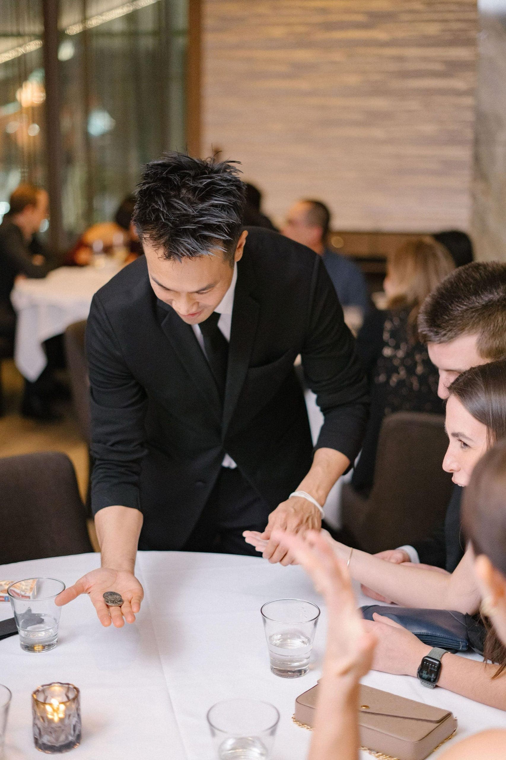 Close-up magic performed at a table during a Vancouver corporate holiday reception