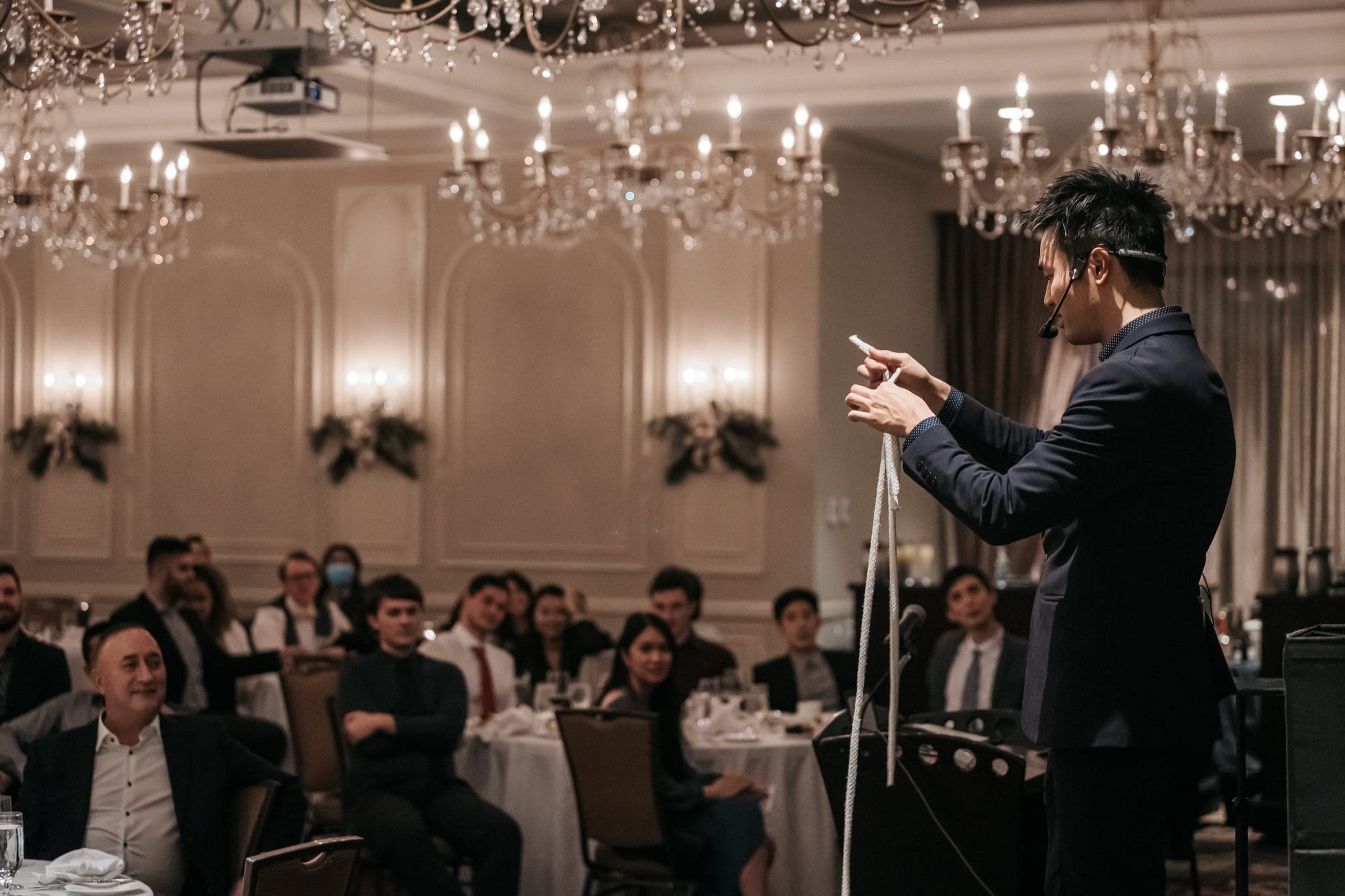 Kel performing to a full seated ballroom under chandeliers at a Vancouver corporate event