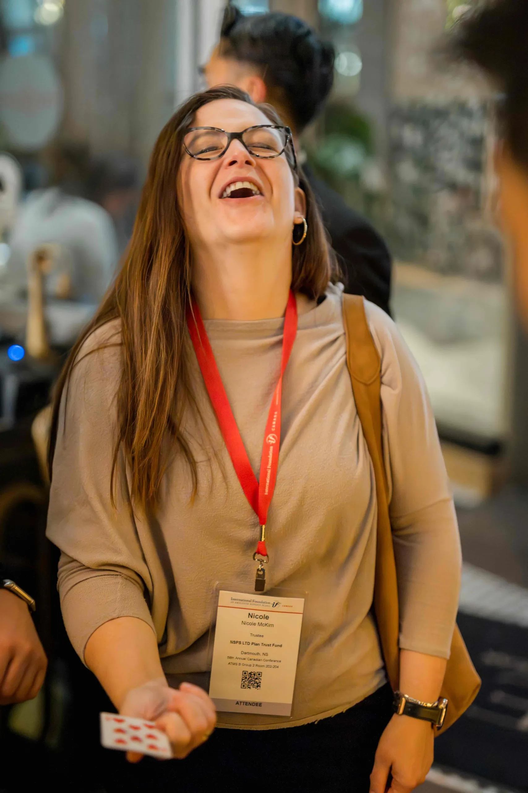Close-up magician performing card magic in a guest's hands at a Vancouver cocktail hour, guest reacting with disbelief