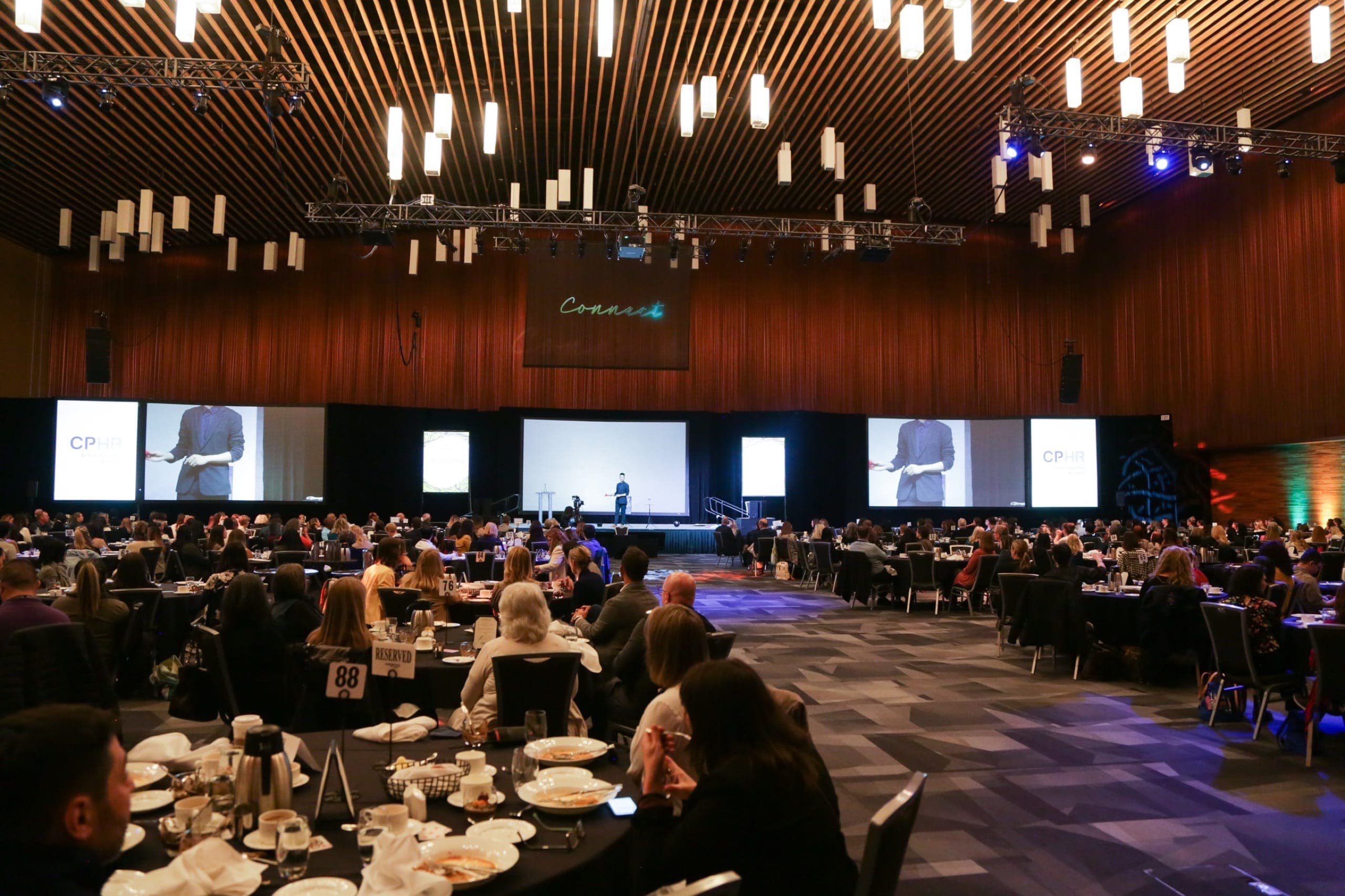 Kel performing on the main stage in front of a full seated audience at a CPHR conference in Vancouver
