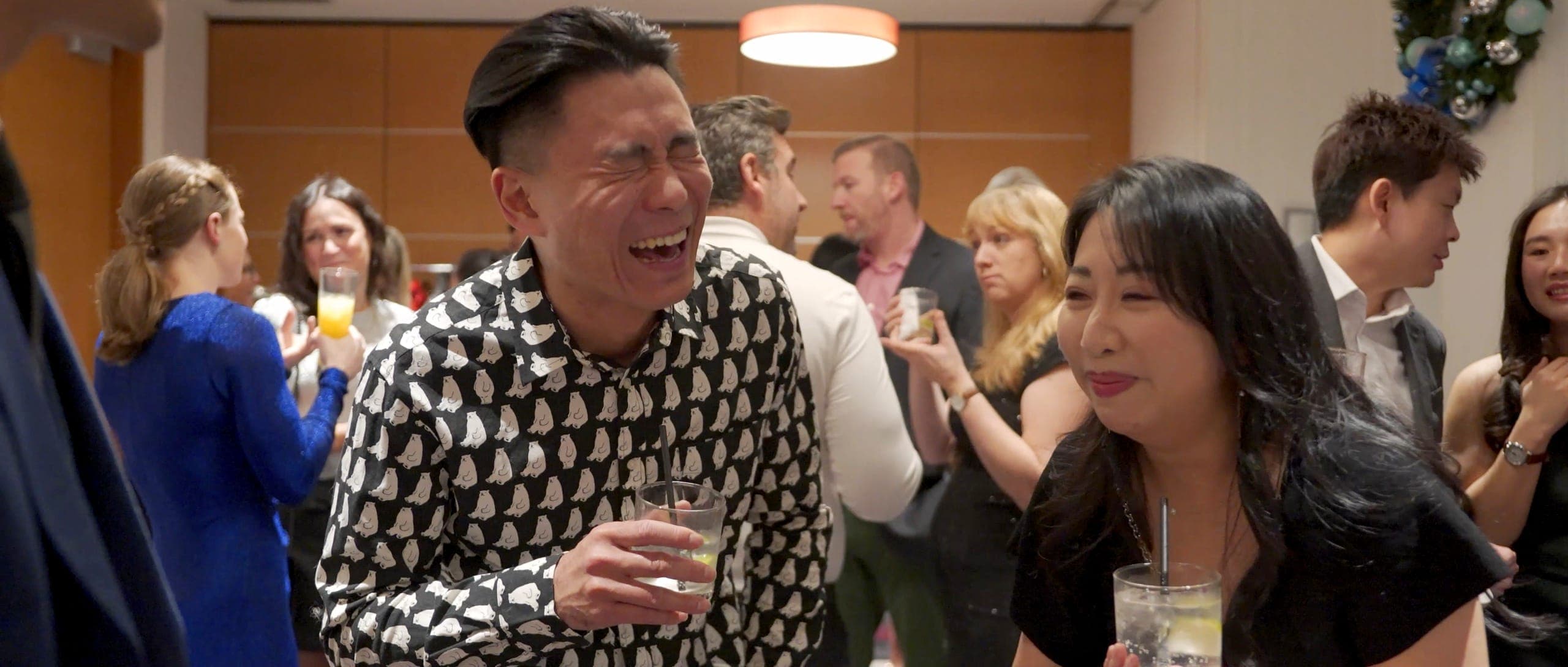 A room of guests laughing together during an evening corporate event