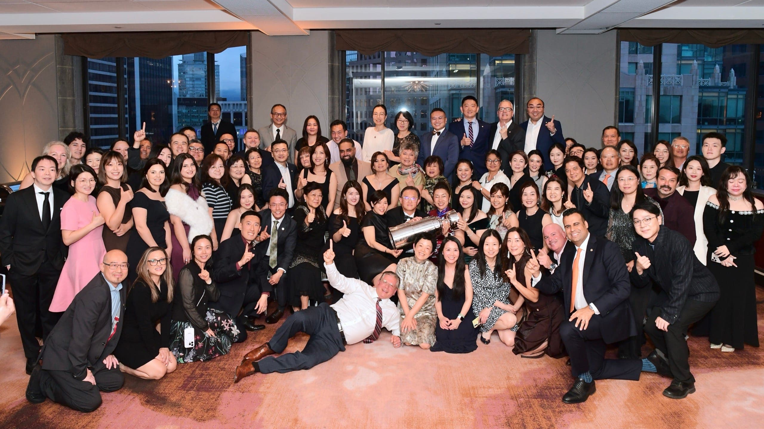 A full company gathered together for a group photo at the end of an evening event