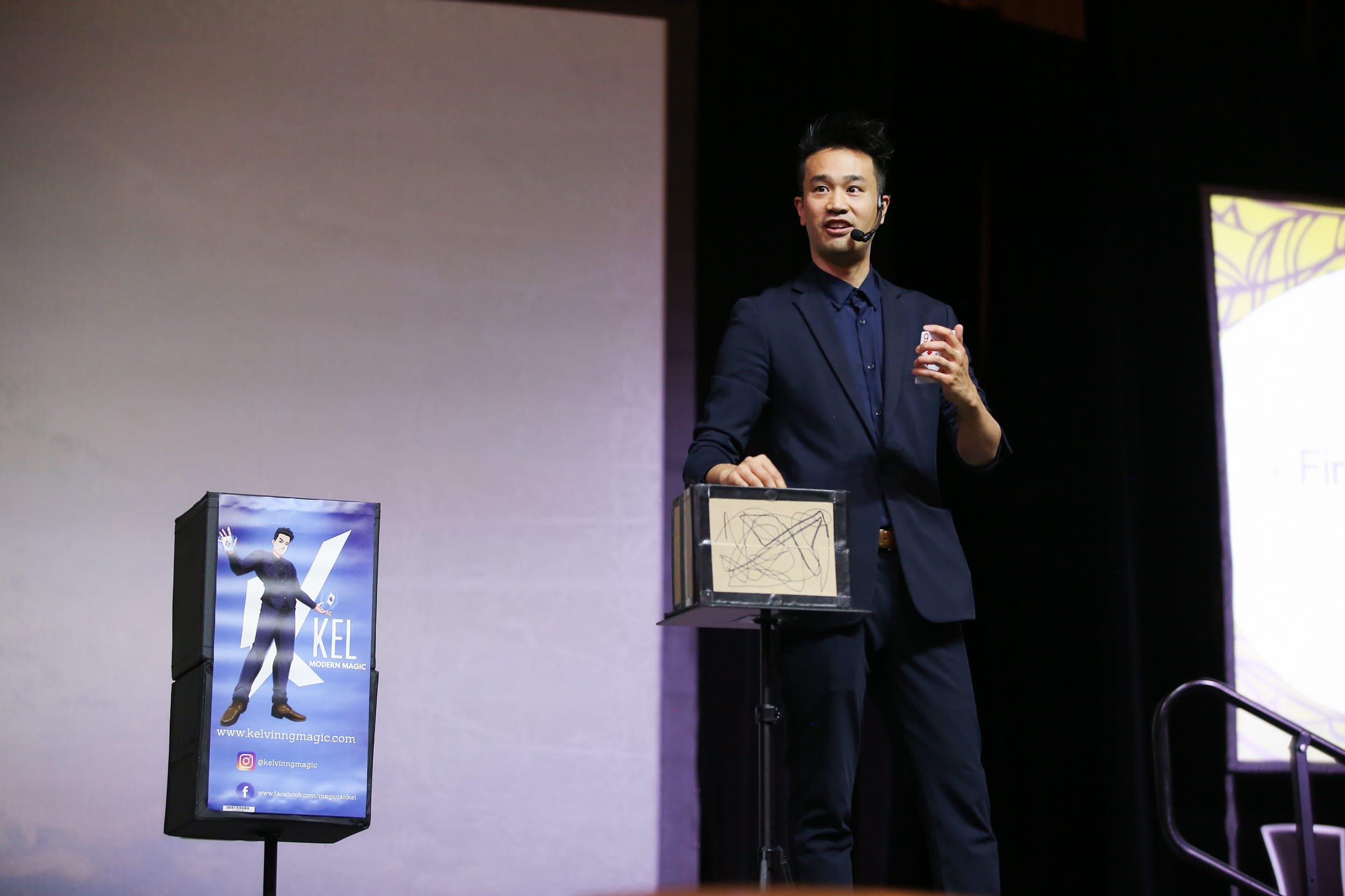 Kel hosting and performing a mentalism routine at a podium during a Vancouver corporate conference