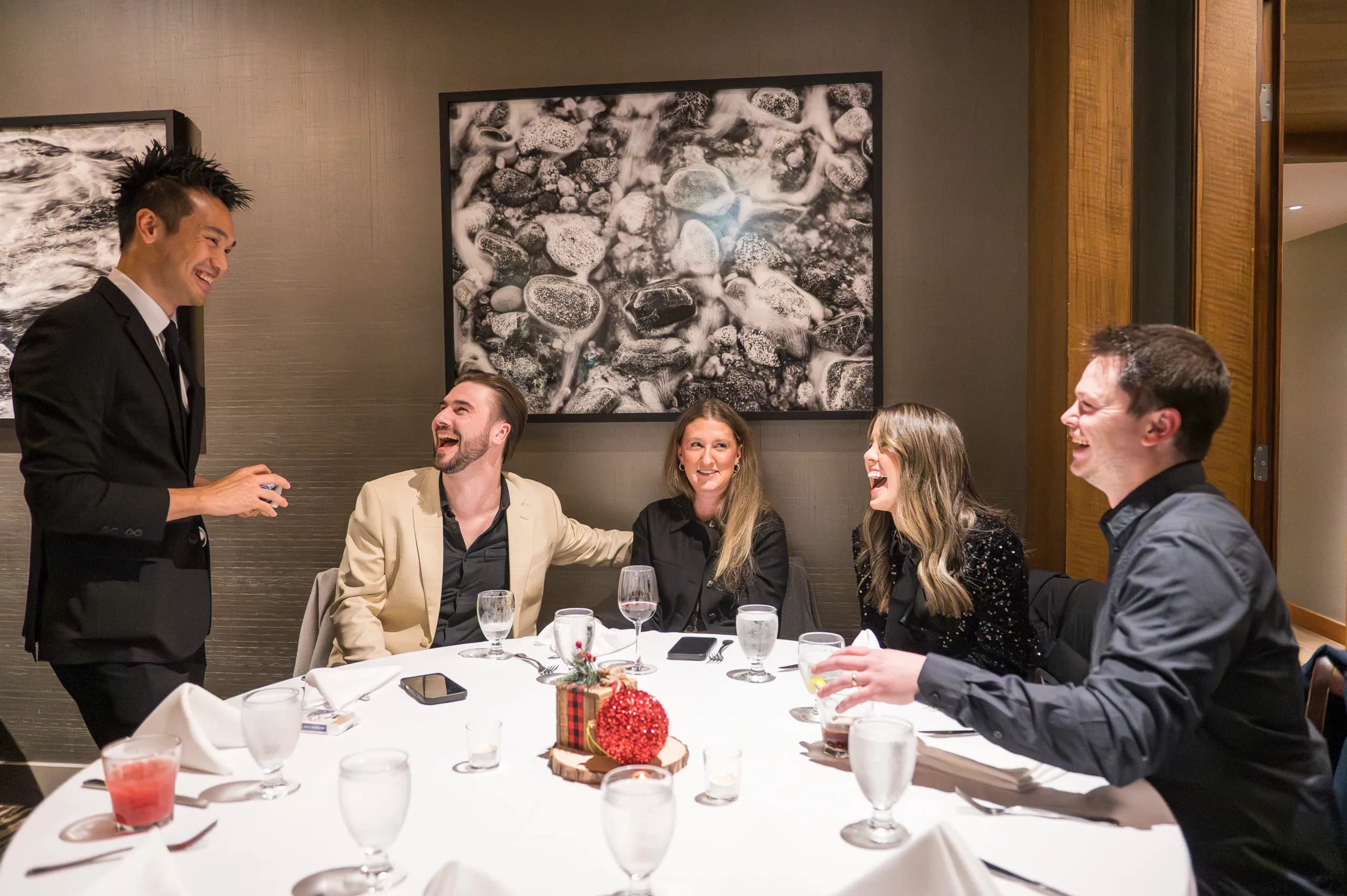 A table of corporate guests laughing together after a close-up magic performance in Vancouver