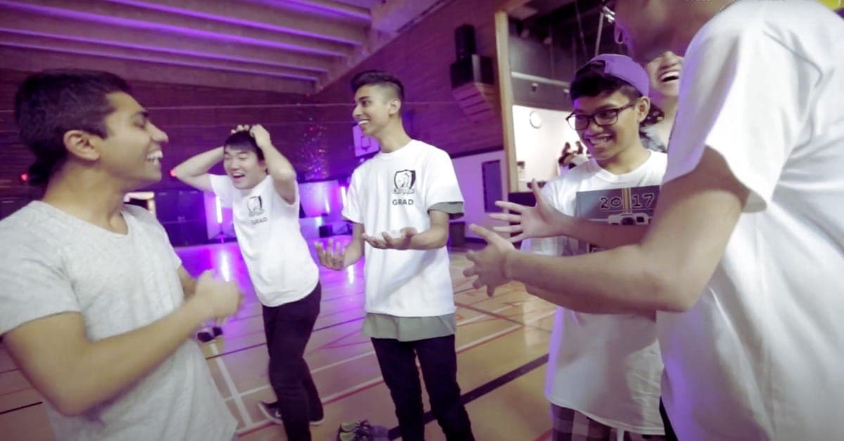Grads reacting to close-up card magic under gym lighting at a Vancouver dry grad event