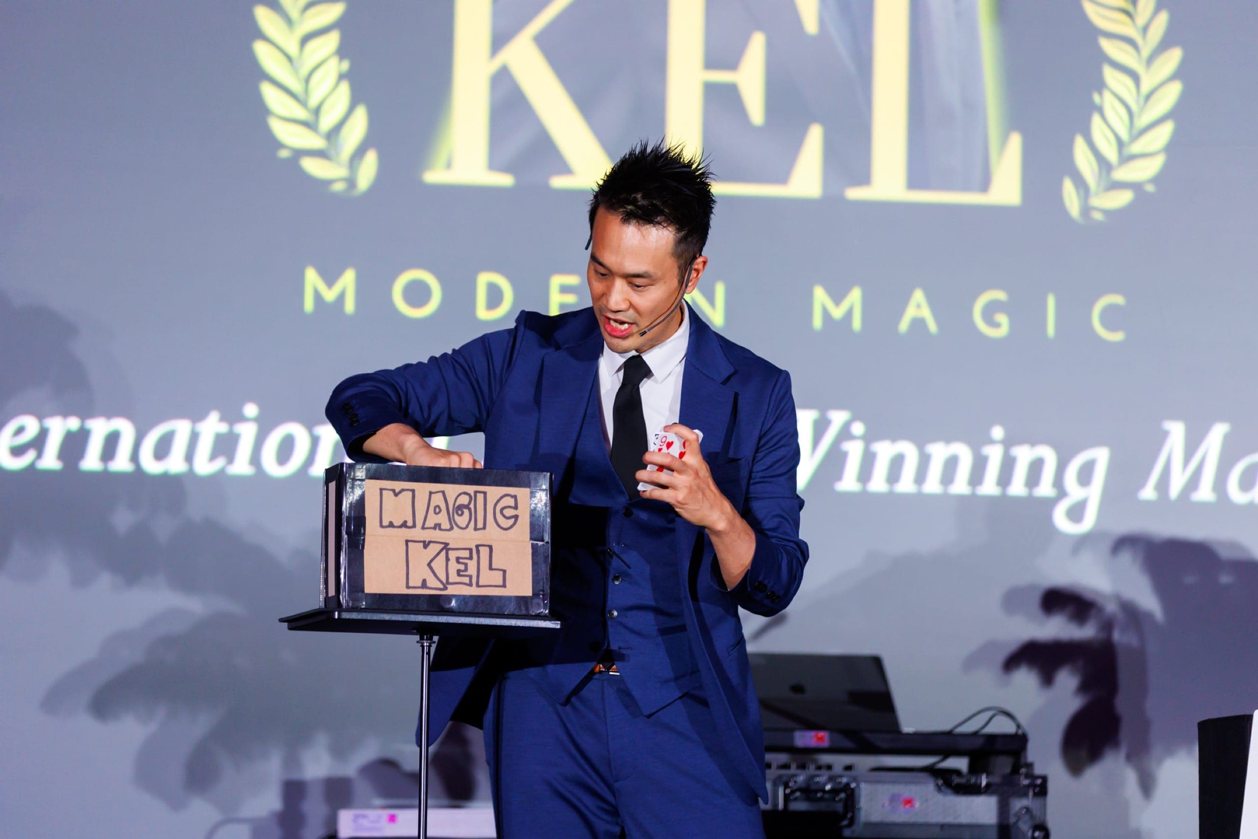 Kel performing on a lit stage during a corporate evening event