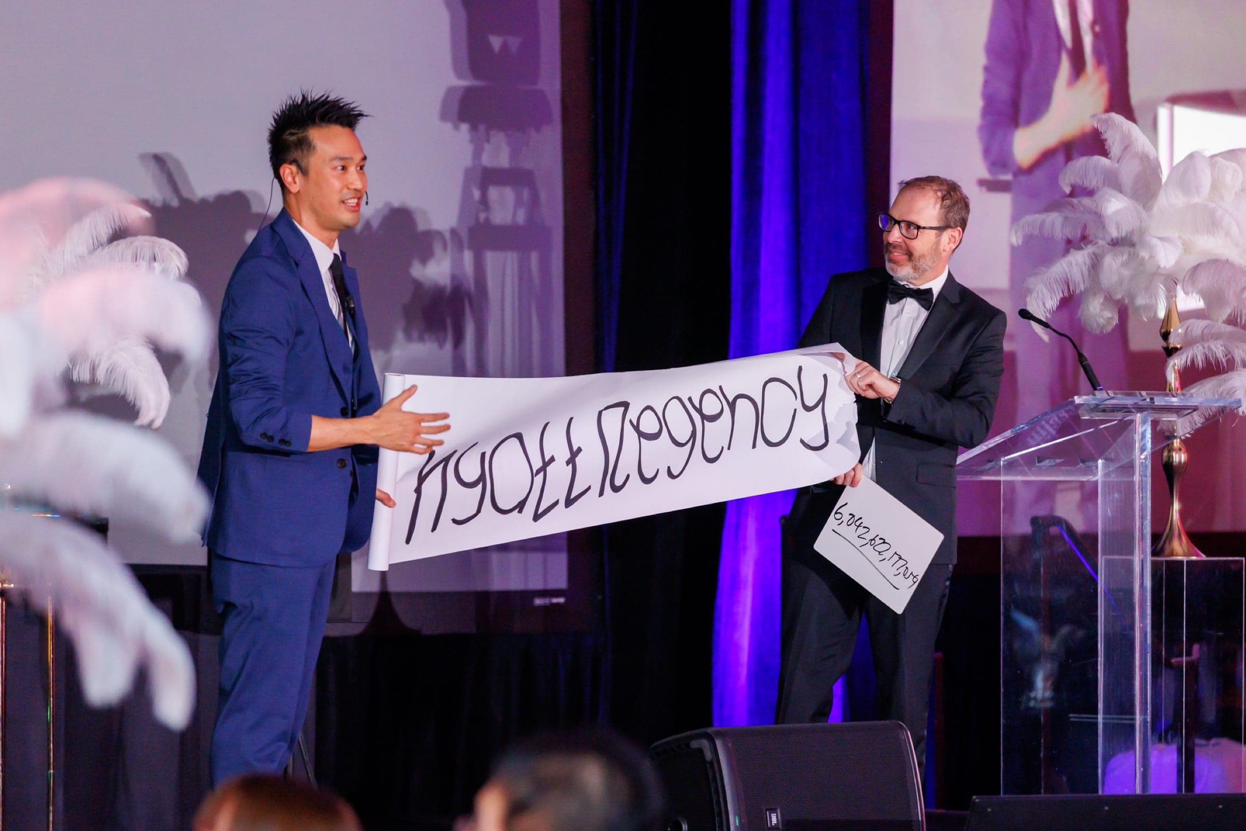 Kel on stage at the moment of the prediction reveal during a Vancouver hotel gala