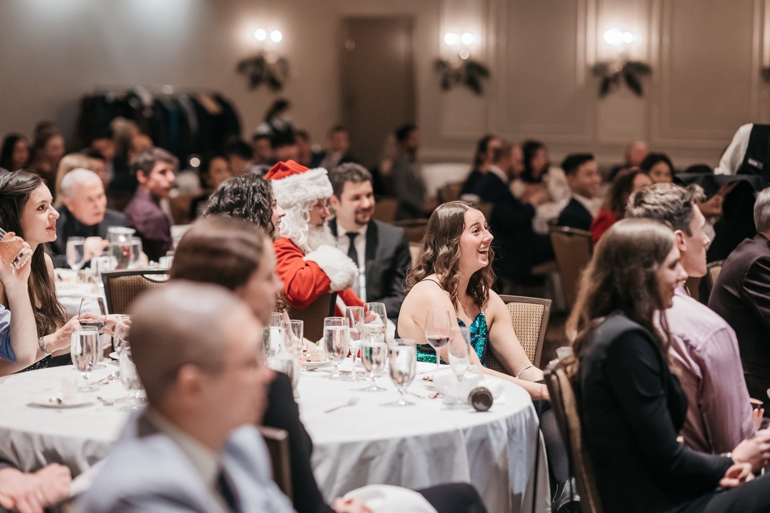 A guest in a sequin dress laughing during close-up magic at a Vancouver corporate holiday party