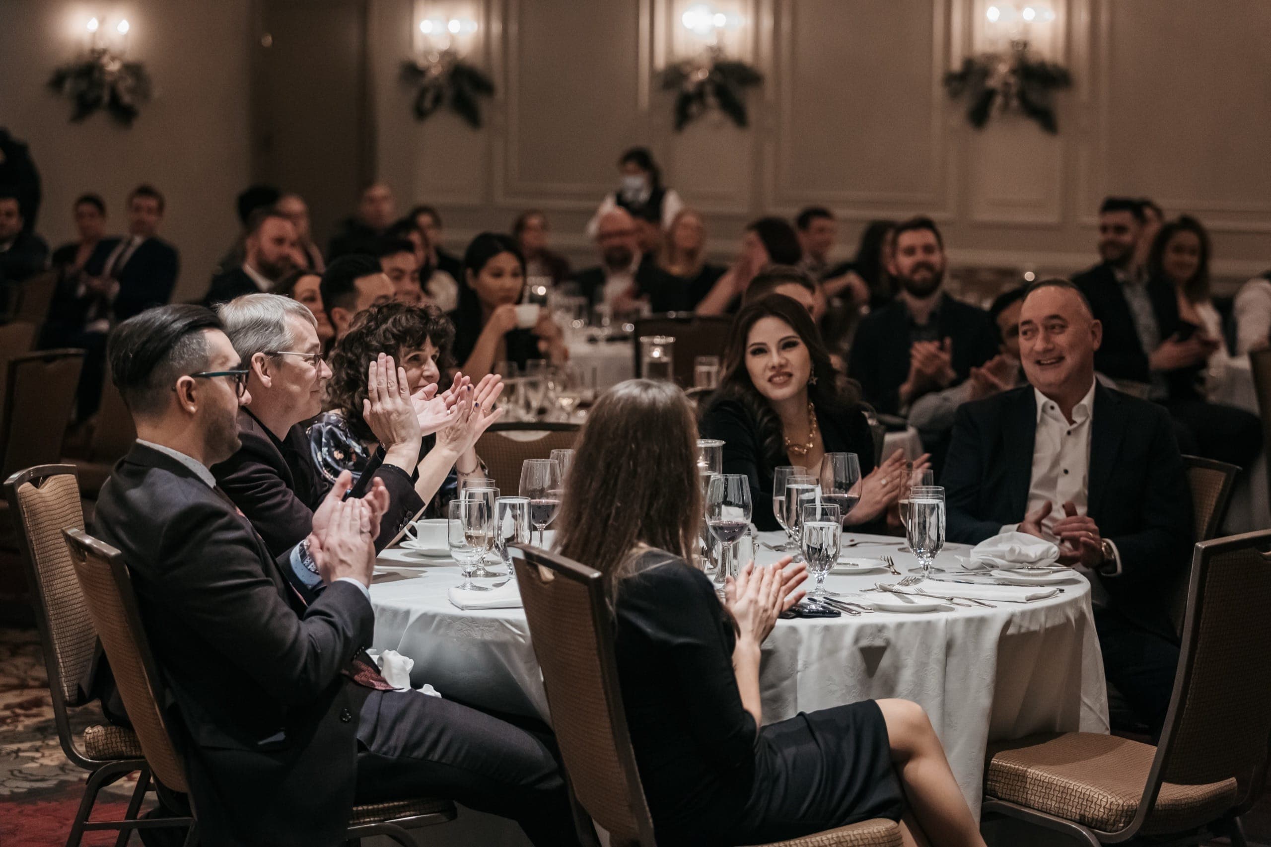 A table of guests applauding together during a Vancouver corporate holiday party