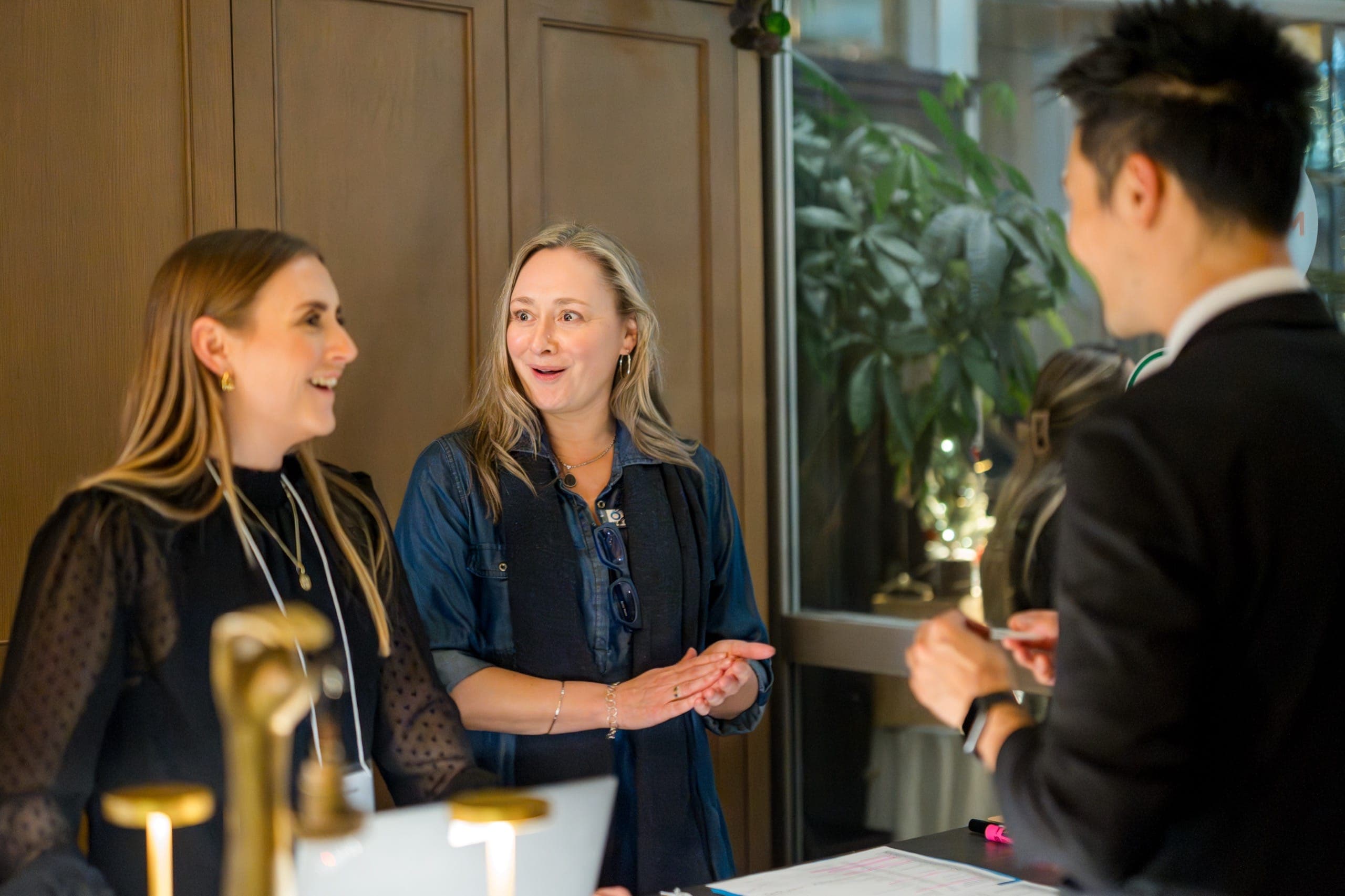 Two guests reacting together, one wide-eyed and one laughing, during close-up coin magic at a Vancouver firm's holiday reception