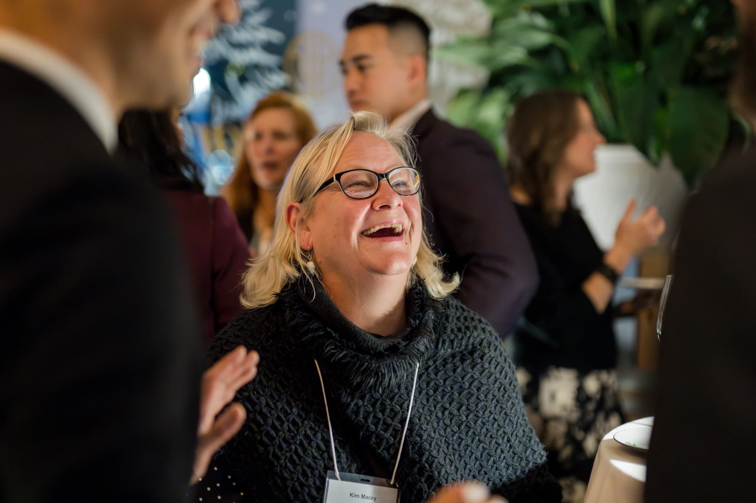 A guest with her head tipped back laughing during close-up magic at a Vancouver corporate party