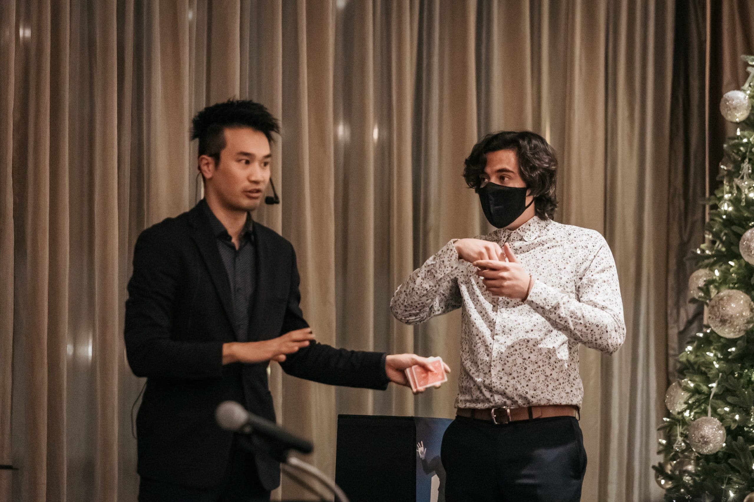 Kel performing a card routine on stage with a volunteer at a corporate event