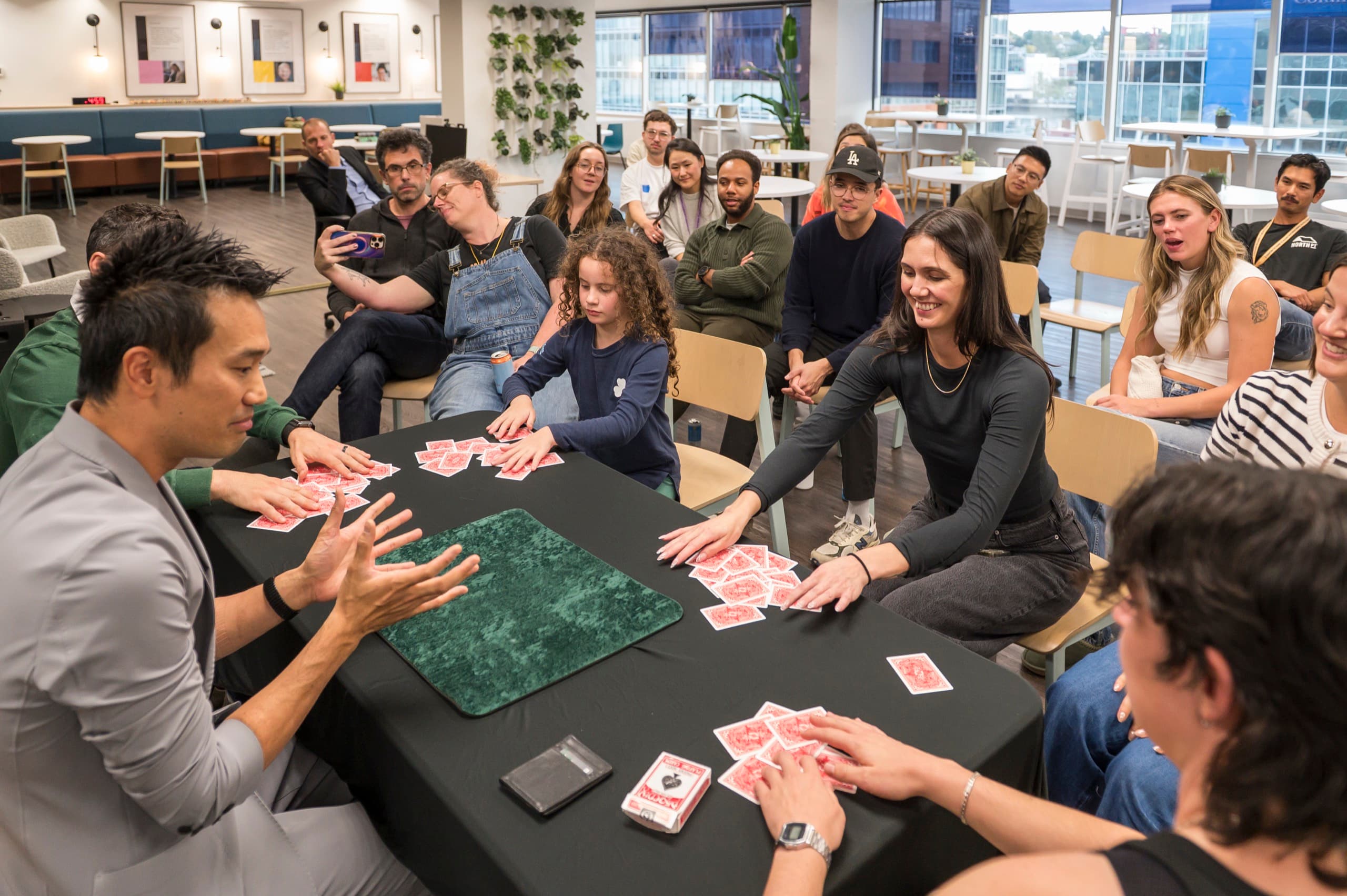 A room of guests gathered around a table watching close-up magic at a corporate event