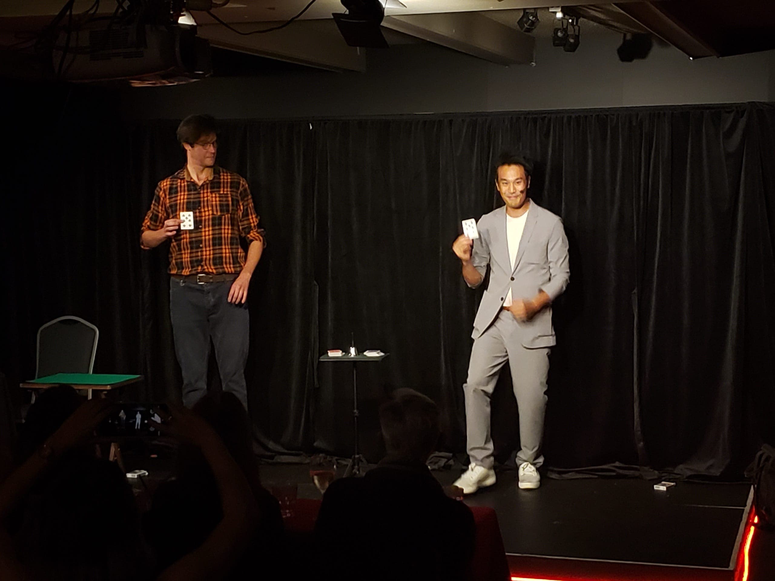 Kel and a volunteer holding up matching cards on a theatre stage at a corporate event
