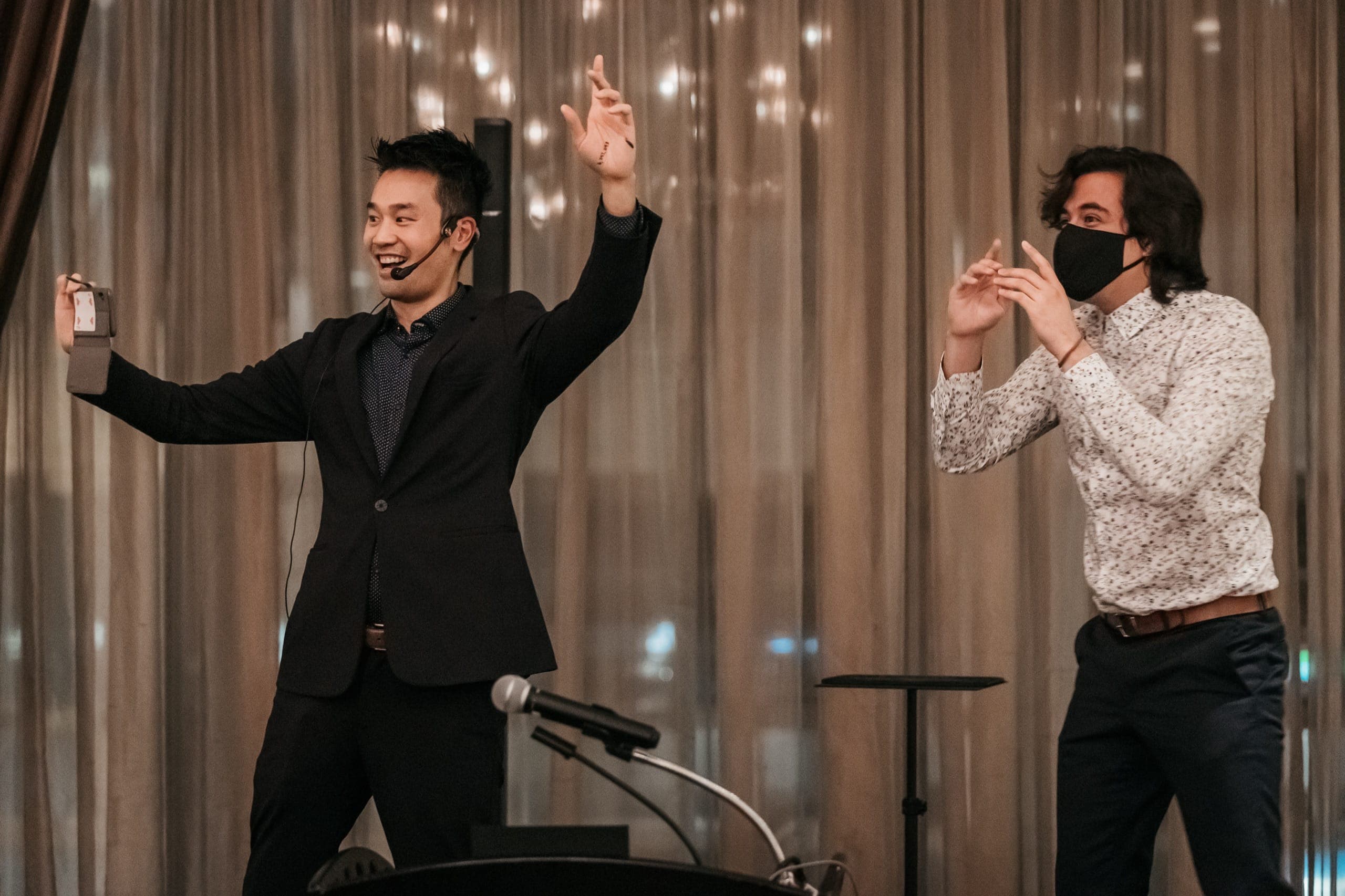 Kel hosting at a podium with arms raised during a reveal at a Vancouver corporate event