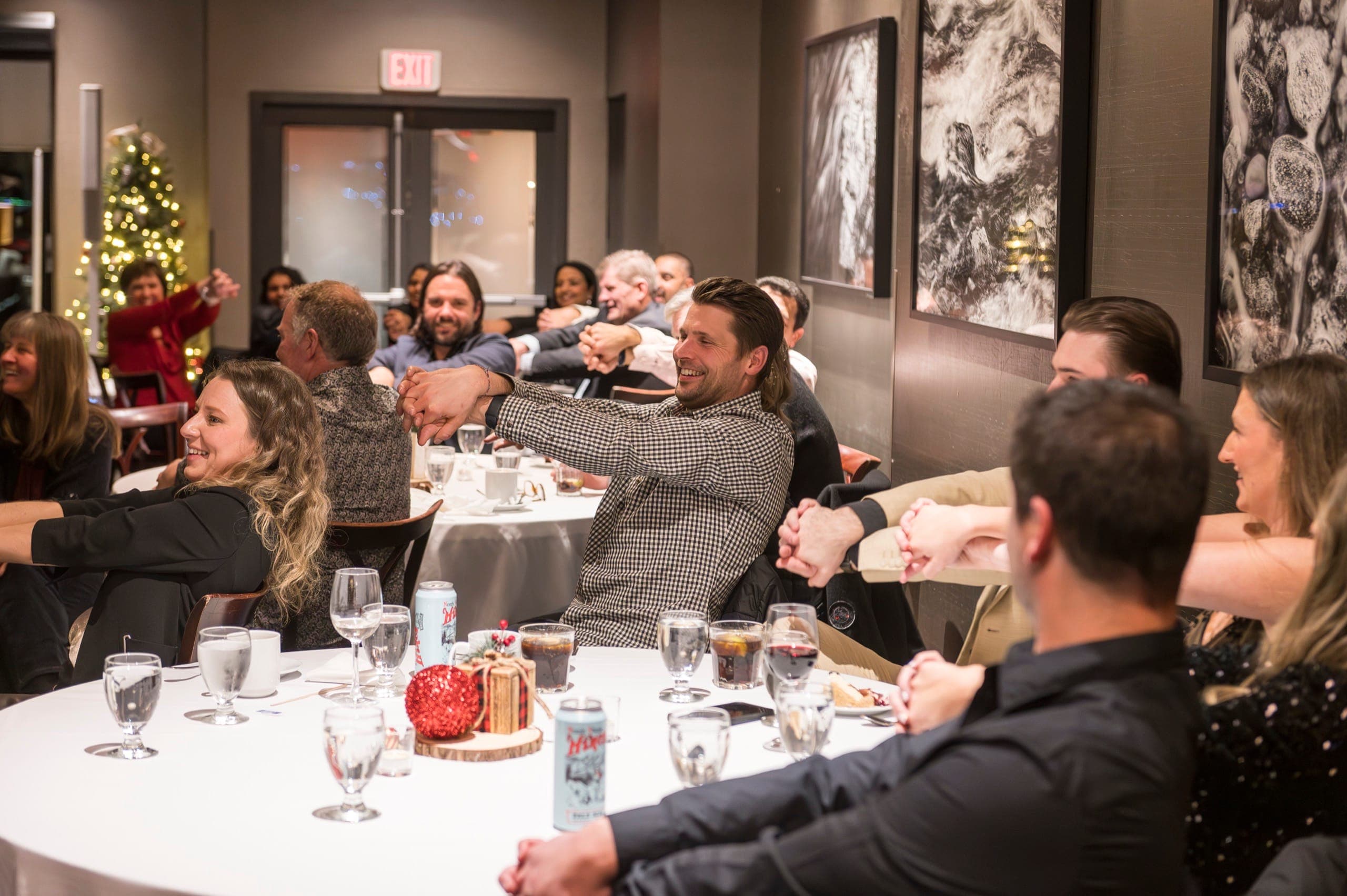 A room of guests with hands linked together, laughing during a group routine at a Vancouver event