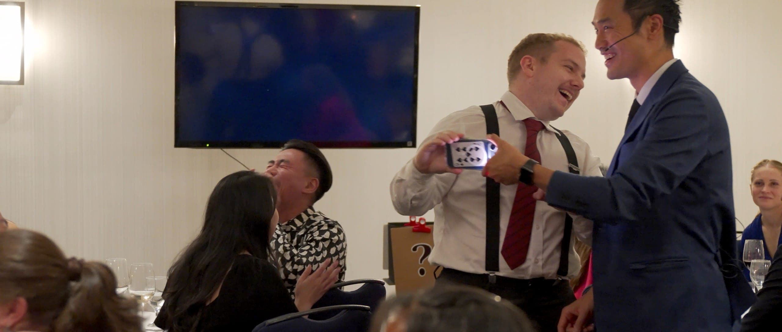 Kel working with a volunteer in front of a seated dinner audience at a Vancouver resource industry evening
