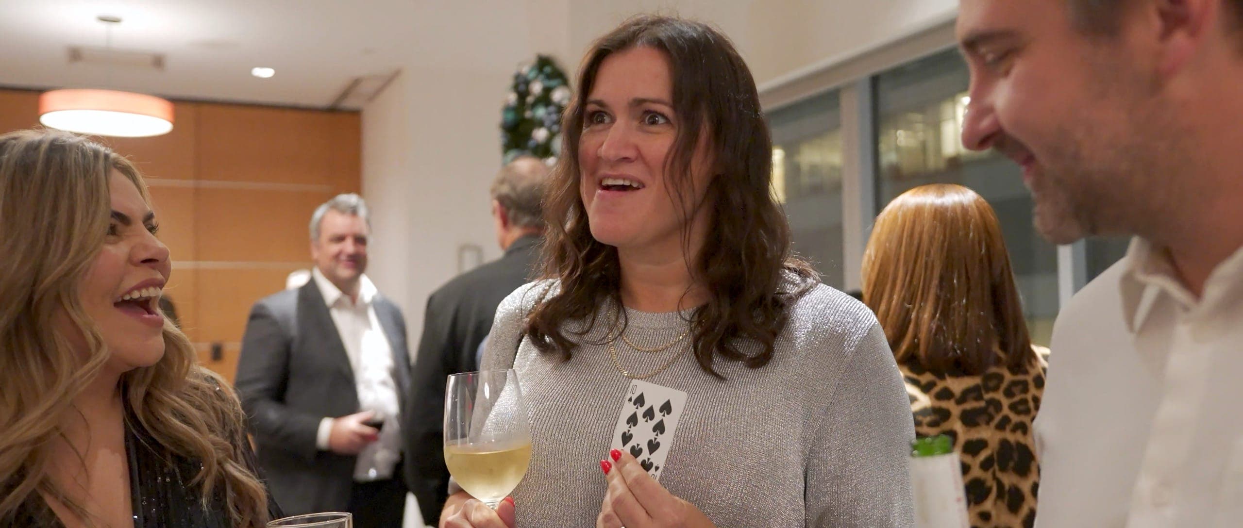 A guest staring at her chosen card in disbelief beside a Christmas tree at the Endeavour Silver party