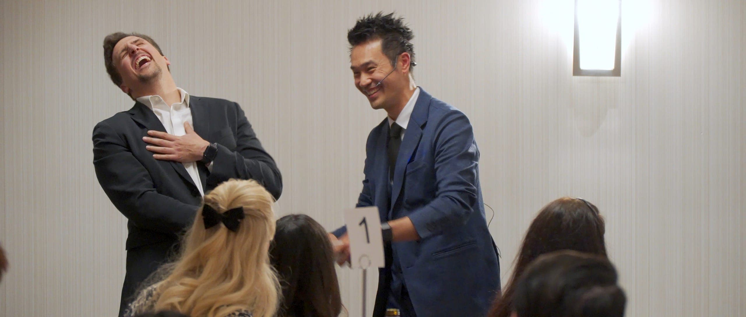 A guest doubled over laughing on stage with Kel during the after-dinner show at a Vancouver resource event
