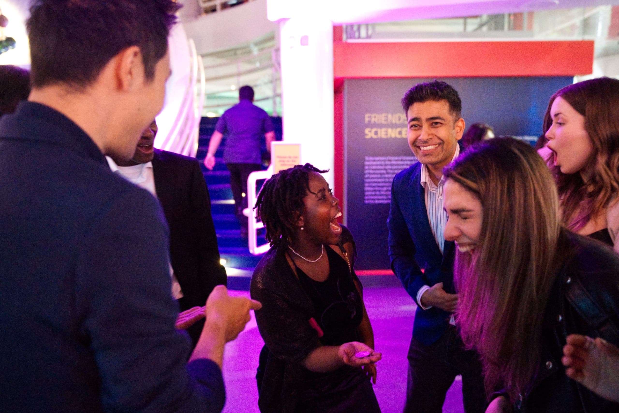 A group of guests reacting with shock and delight during close-up magic at a Vancouver event