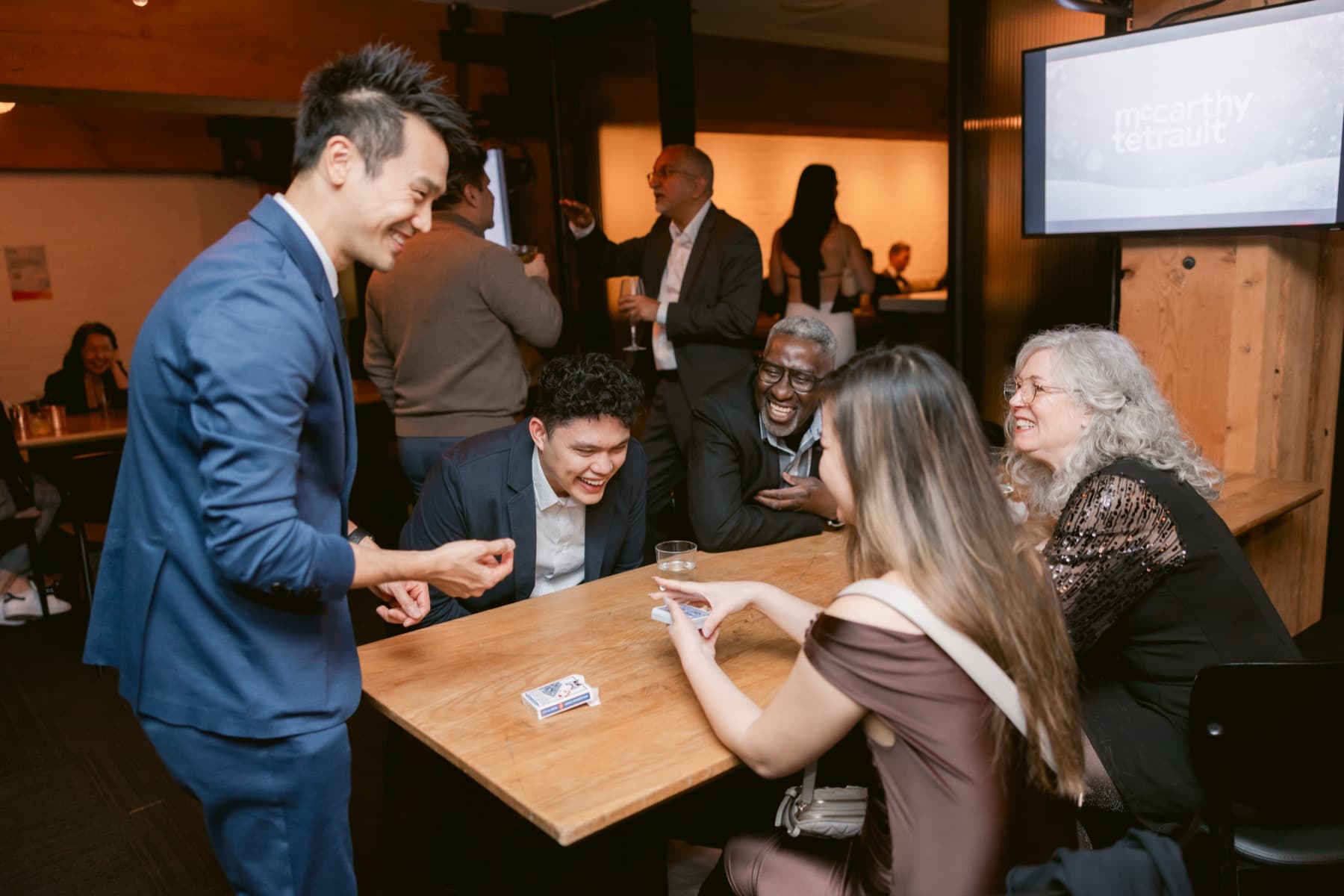 A table of guests cracking up during close-up card magic at a private celebration