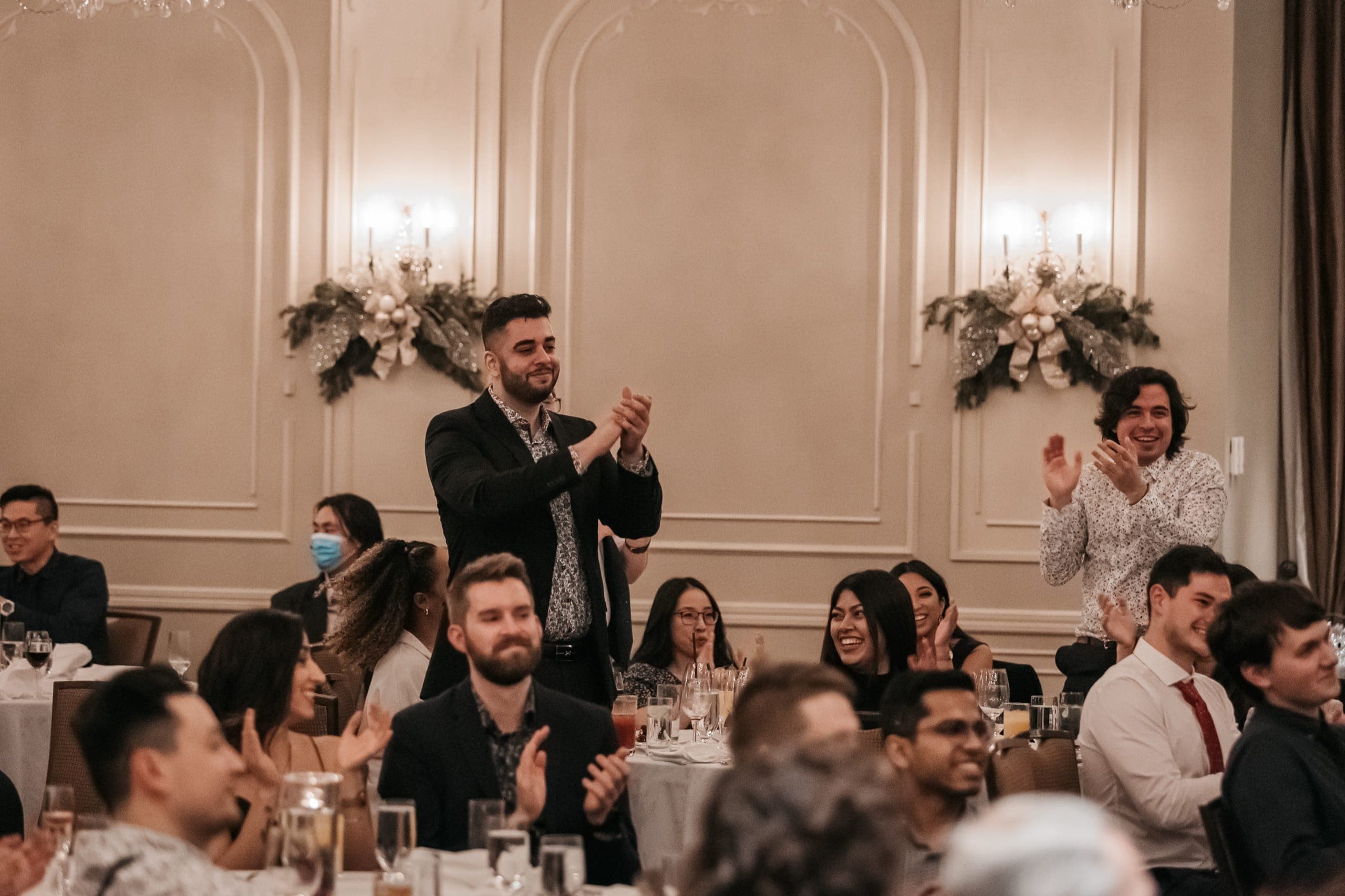 Guests rising to their feet applauding at the end of a magic show at a Vancouver industry event