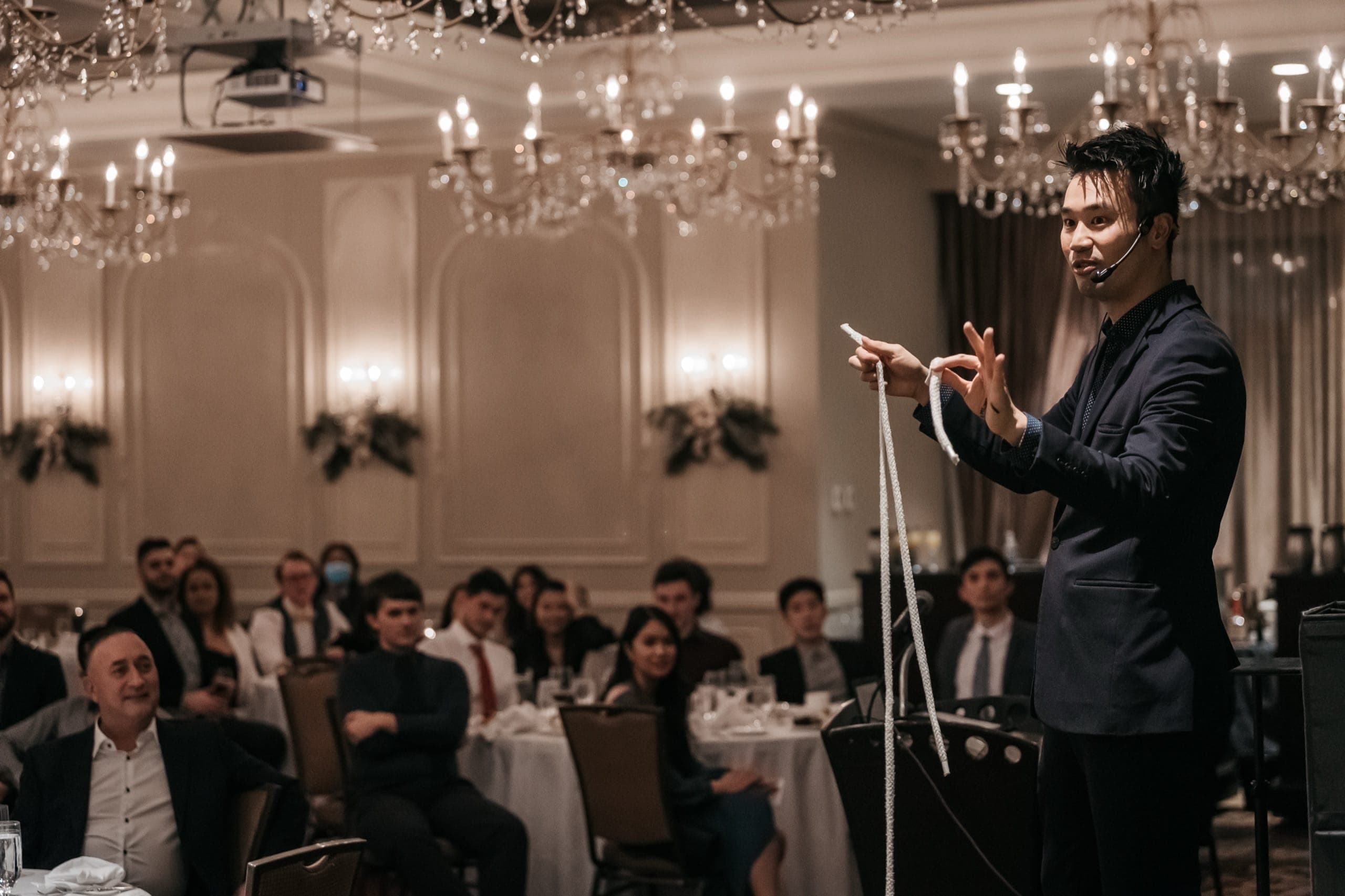 Kel performing a rope routine under chandeliers to a full seated ballroom at a Vancouver corporate event