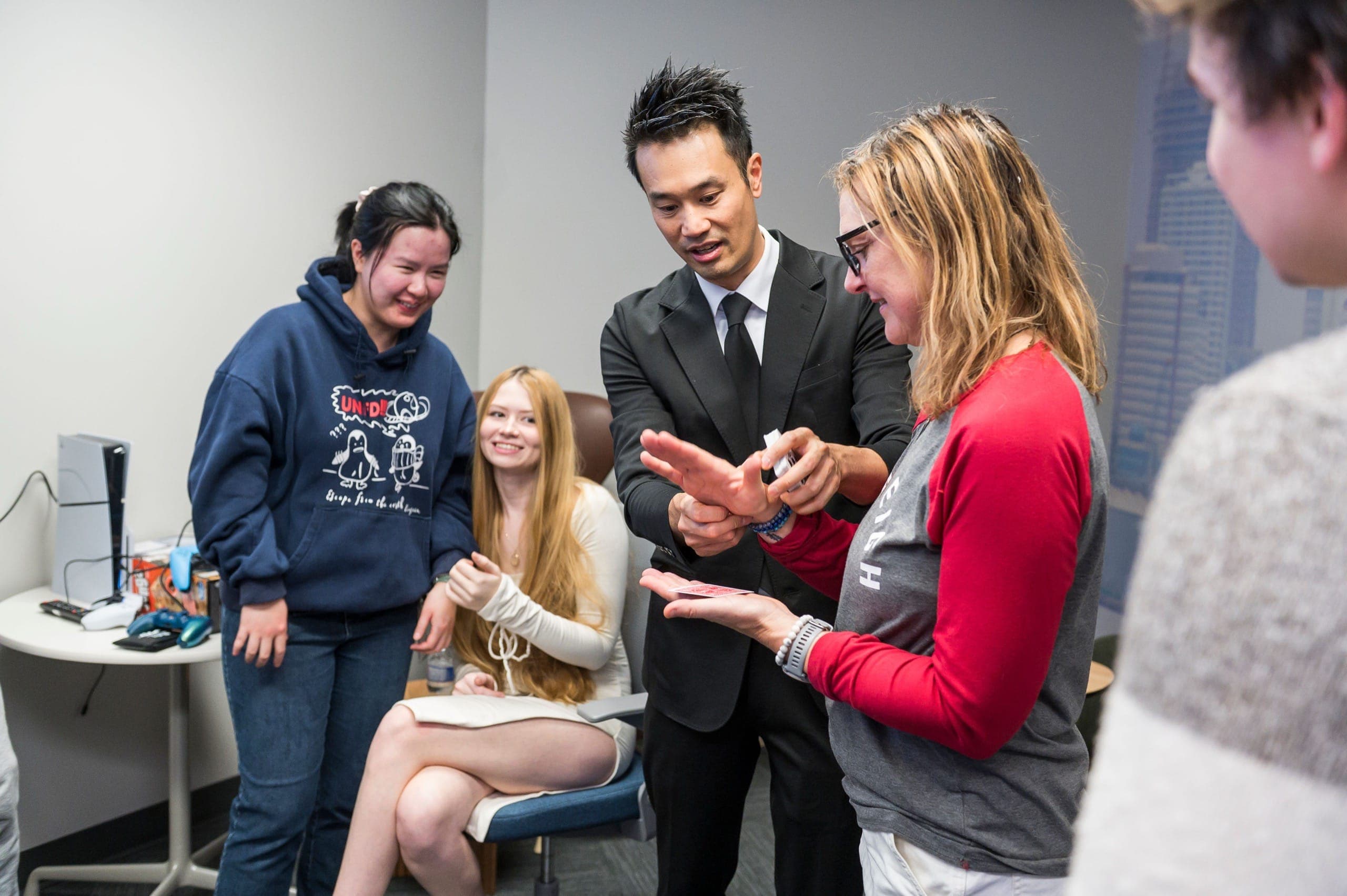 Kel guiding a guest's wrist as a chosen card rests on her open palm at a Vancouver tech office event