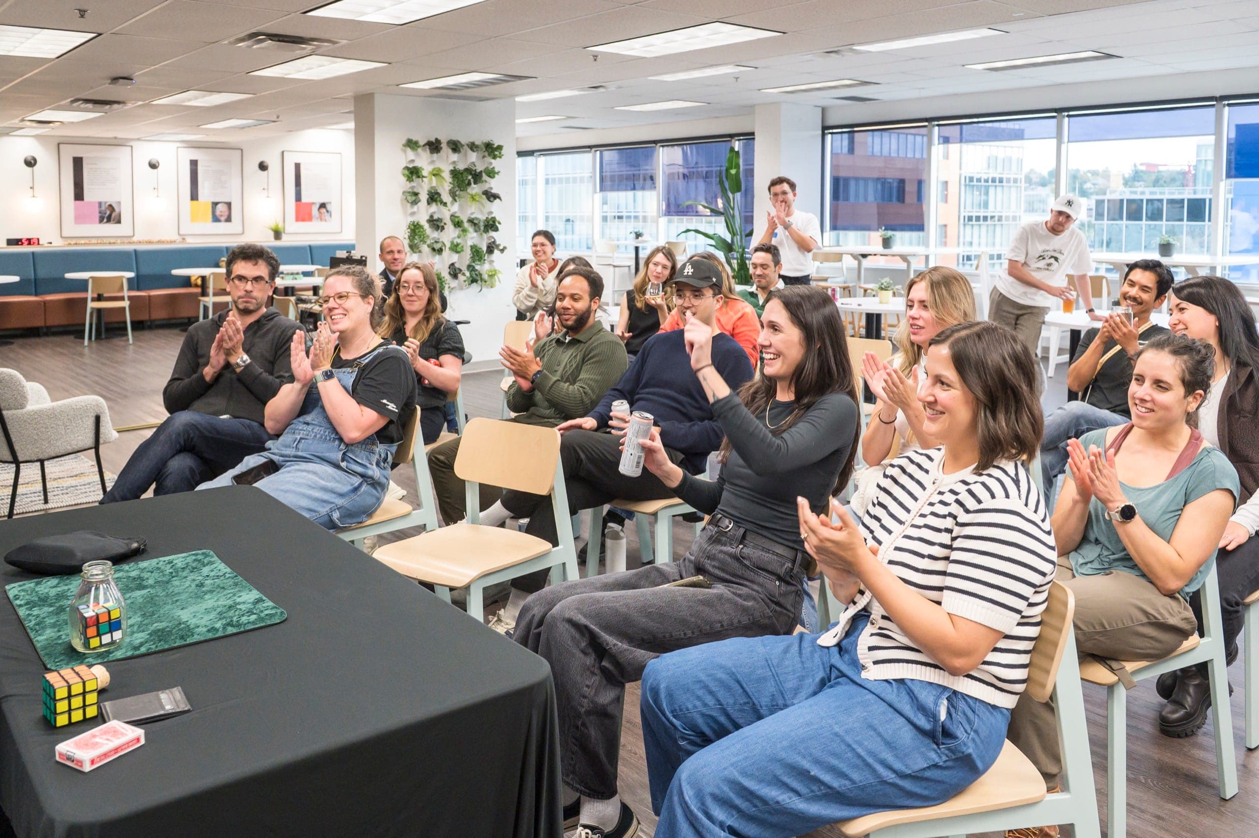 A full room of tech company staff applauding after a magic routine at a Vancouver office event
