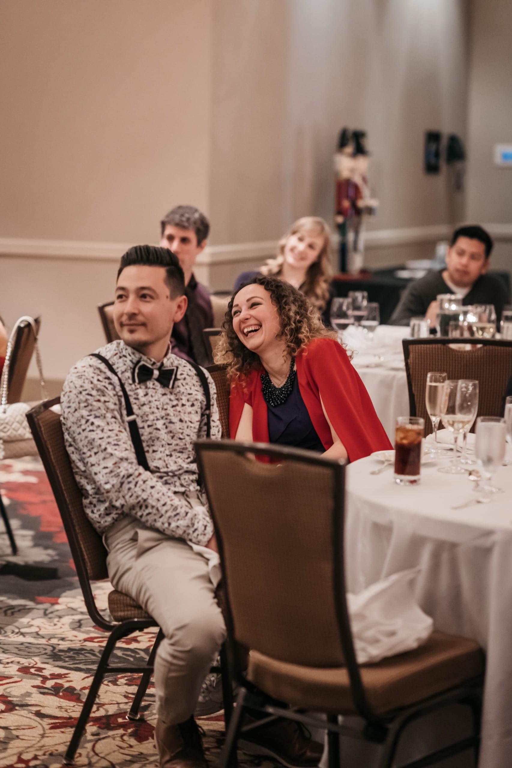 A guest thrown back laughing during close-up magic at a Vancouver company holiday party