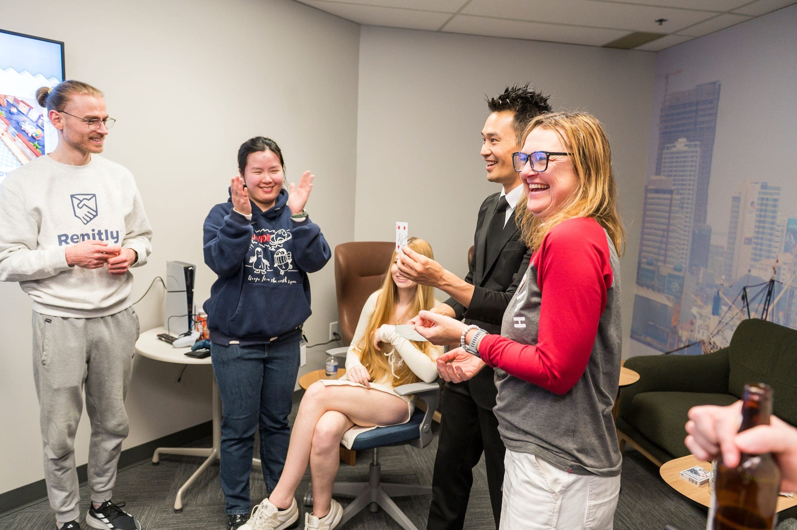 Remitly staff laughing and applauding as Kel reveals a chosen card at their Vancouver office party