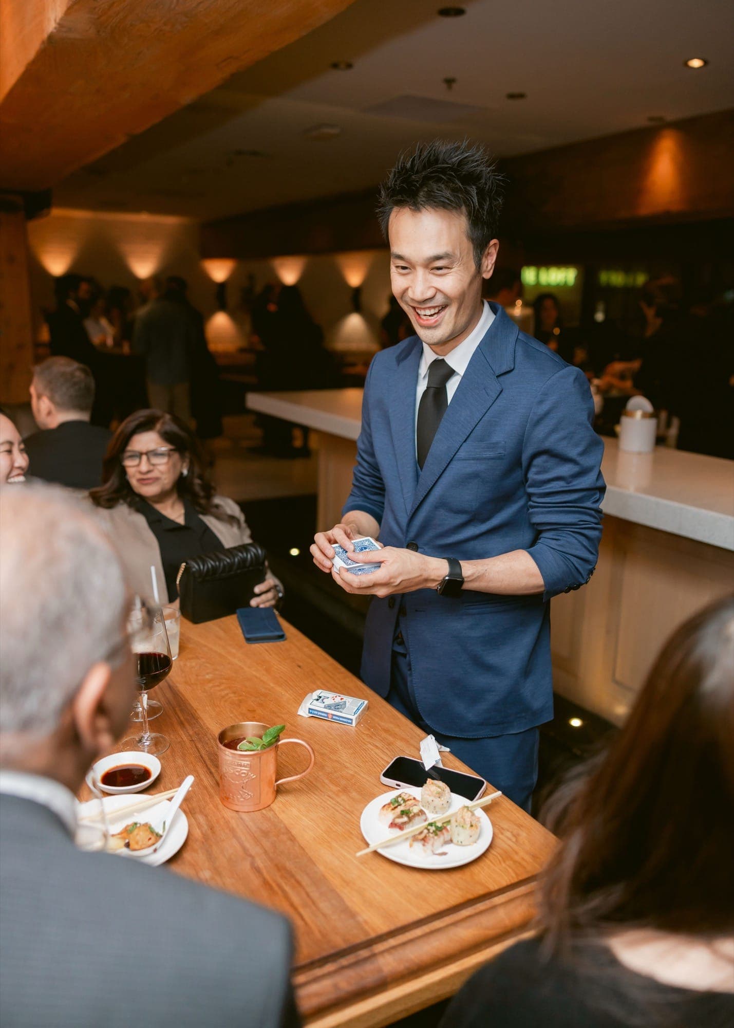 Kel performing close-up card magic for guests at a restaurant table in Vancouver