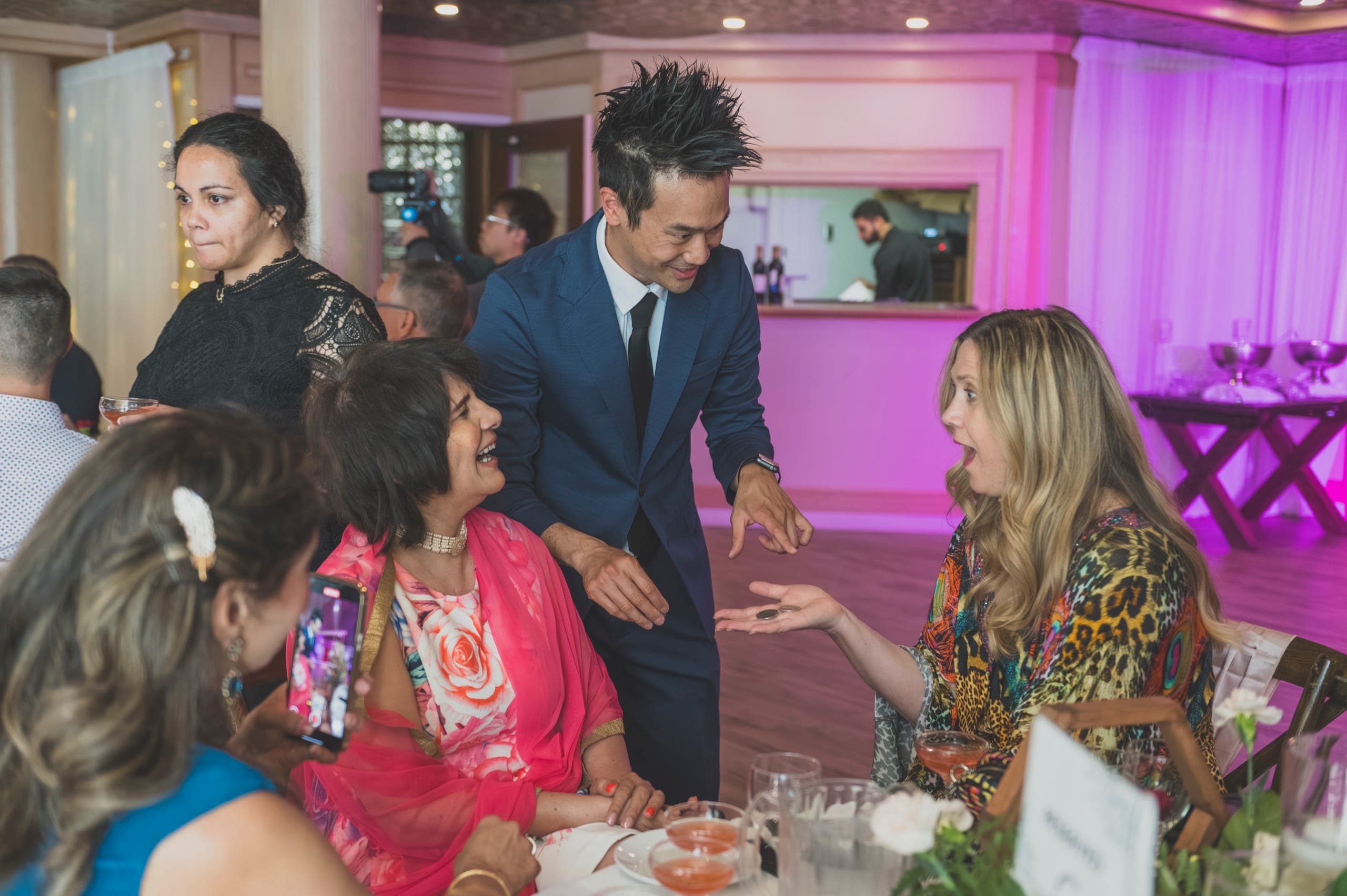 Wedding guests reacting to a coin trick during Alice and Tyler's reception at Newlands Golf Club in Langley
