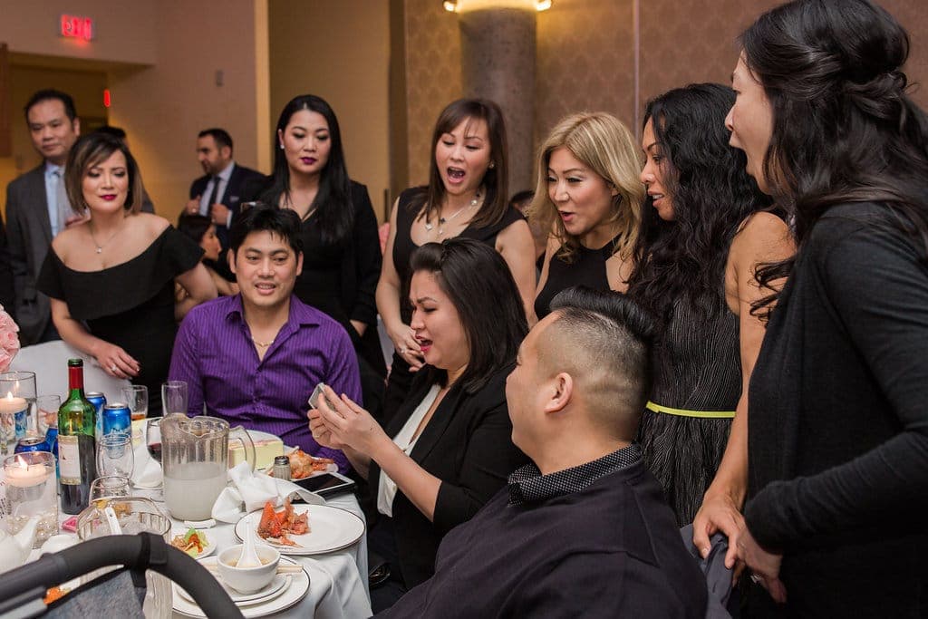 A table of wedding guests reacting with amazement to close-up card magic during dinner