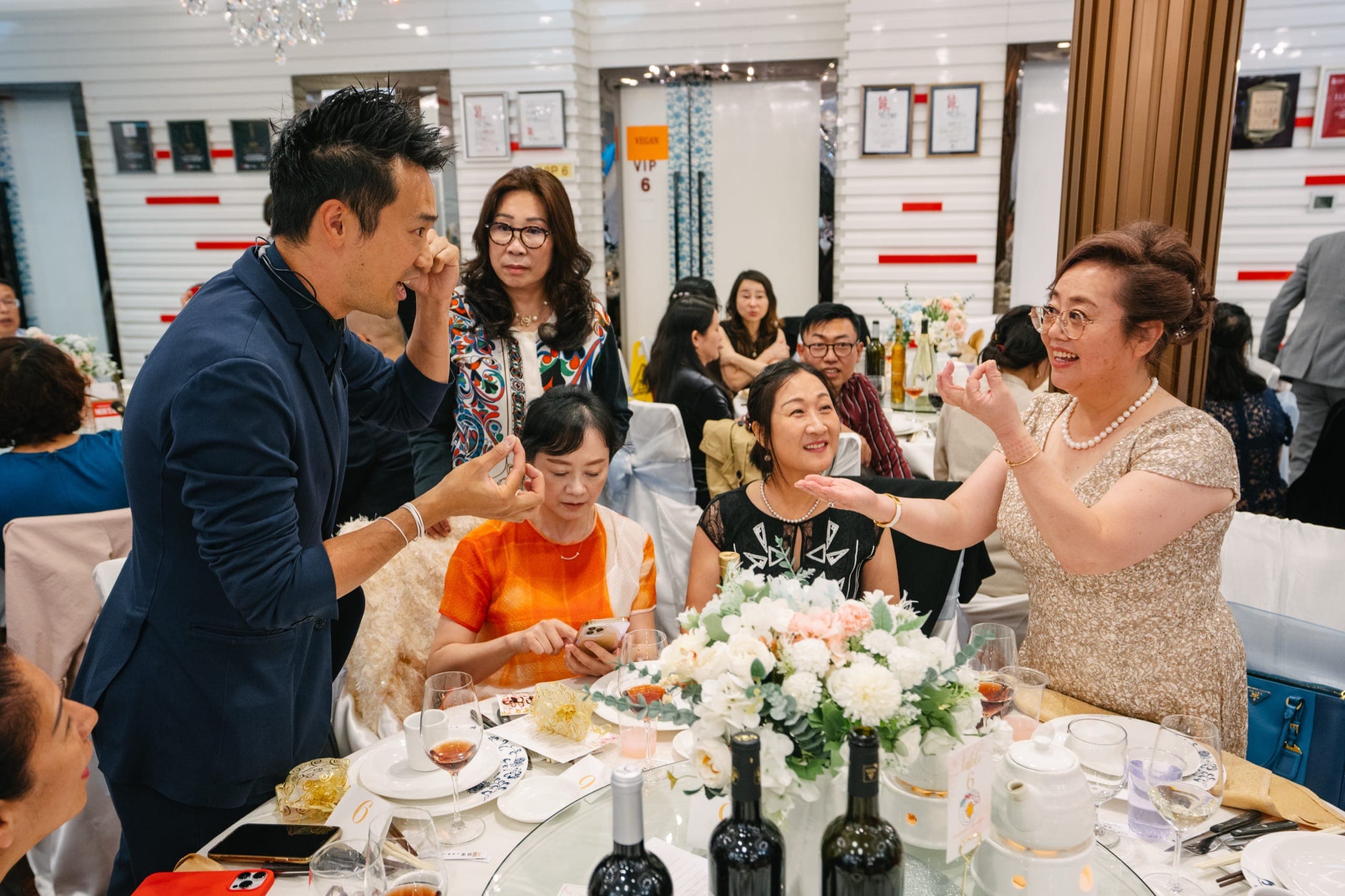 Multiple generations of family reacting with amazement to close-up magic at Jennifer and Robert's Chinese wedding banquet in Vancouver