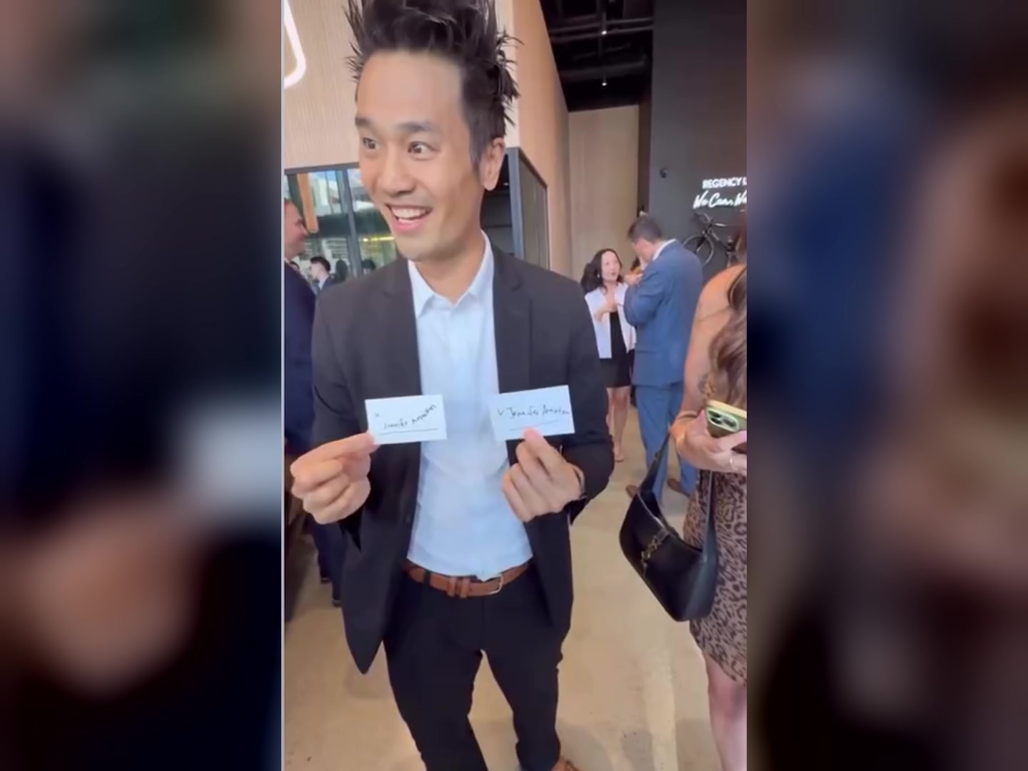Kel smiling and holding up two matching signed cards in the Regency Lexus showroom