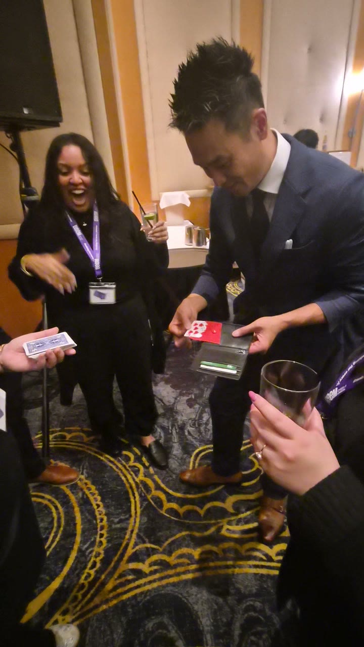 A Beem Wealth guest laughing in shock as Kel reveals a card during close-up magic in Burnaby