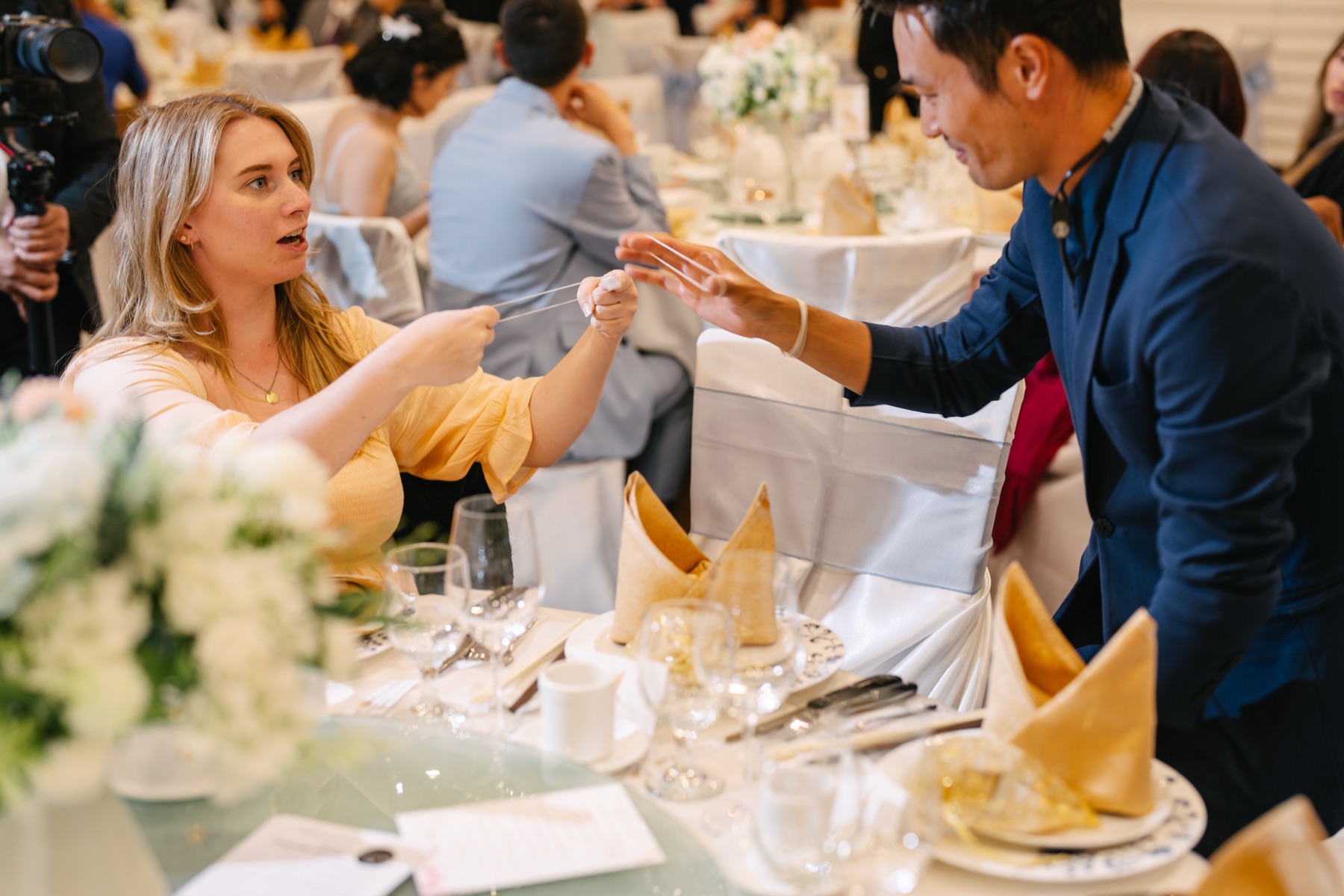 A wedding guest stretching an elastic band held out by Kel during close-up magic at a Richmond banquet