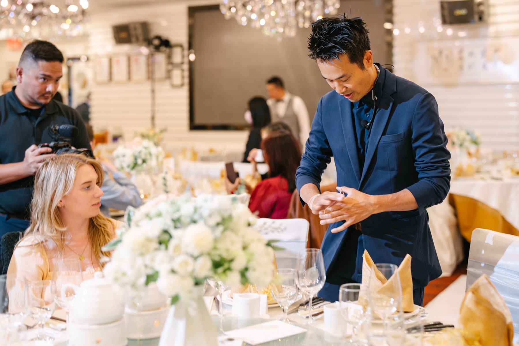 Kel performing close-up magic at a guest table during Jennifer and Robert's wedding banquet at Chef Tony in Richmond