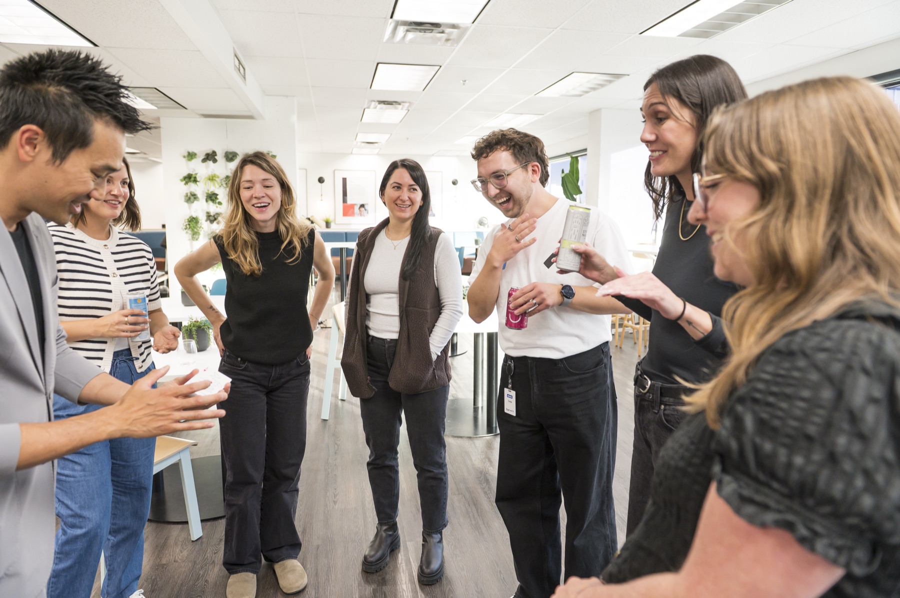Kel performing close-up magic to a standing circle of Thinkific employees during an office happy hour